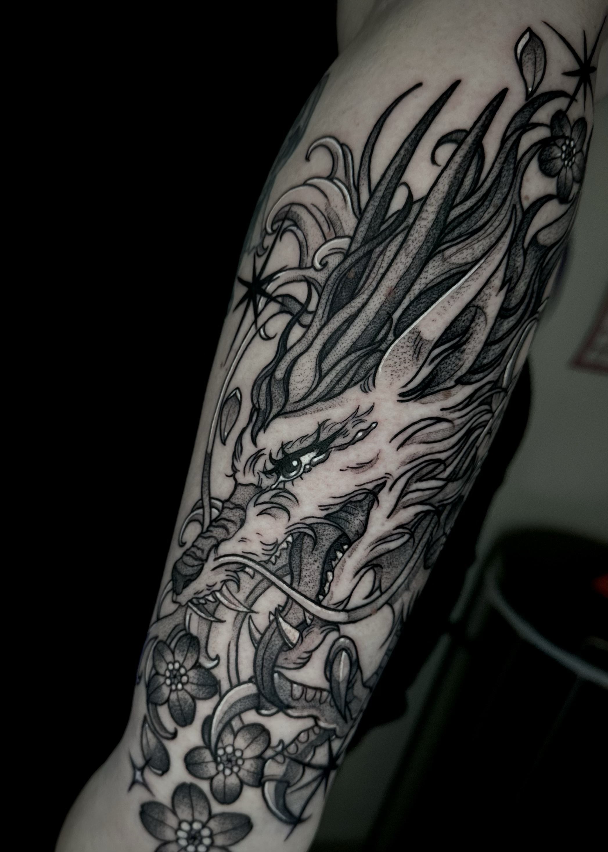 Black and grey, blackwork, forearm tattoo of Haku from Spirited away with florals and stars  by Portland Tattoo artist at Upper Moon Tattoo Rae Syndulla 