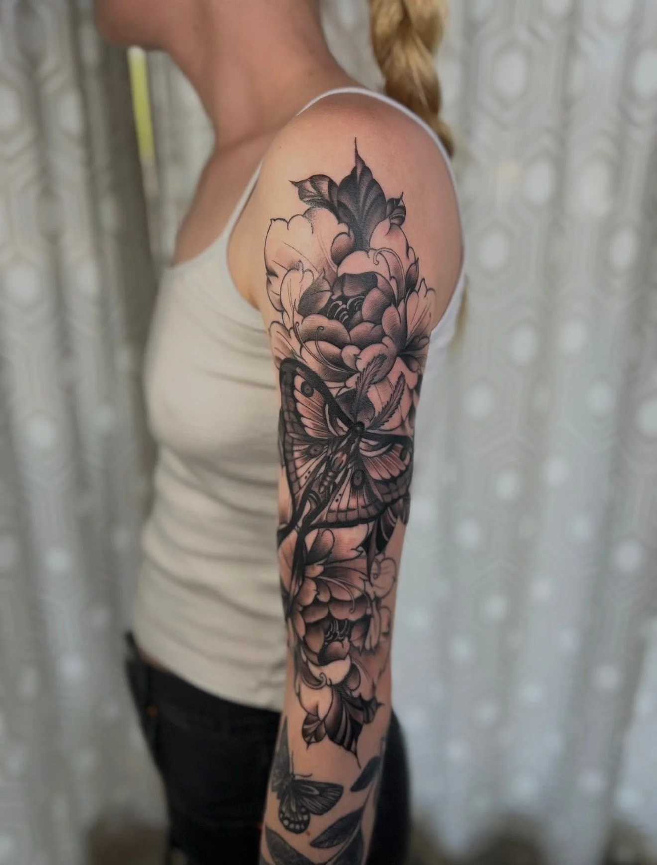 A black and grey half sleeve tattoo on the arm of a moth/ butterfly with peony flowers by portland tattoo artist at Upper Moon Tattoo, Daniel Aispuro