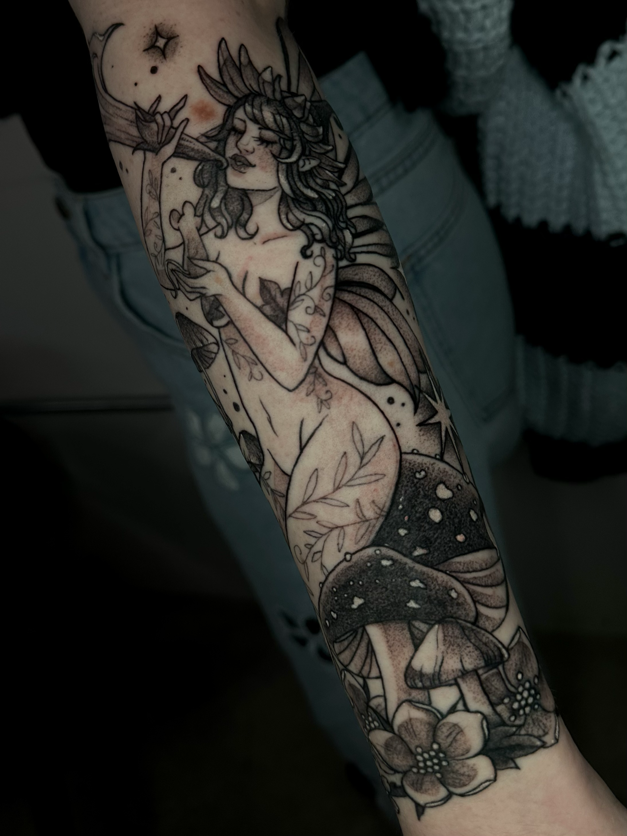 Black and grey finalize fairy on the forearm with florals, mushrooms, whimsical lady tattoo by Portland Tattoo artist at Upper Moon Tattoo Rae Syndulla 