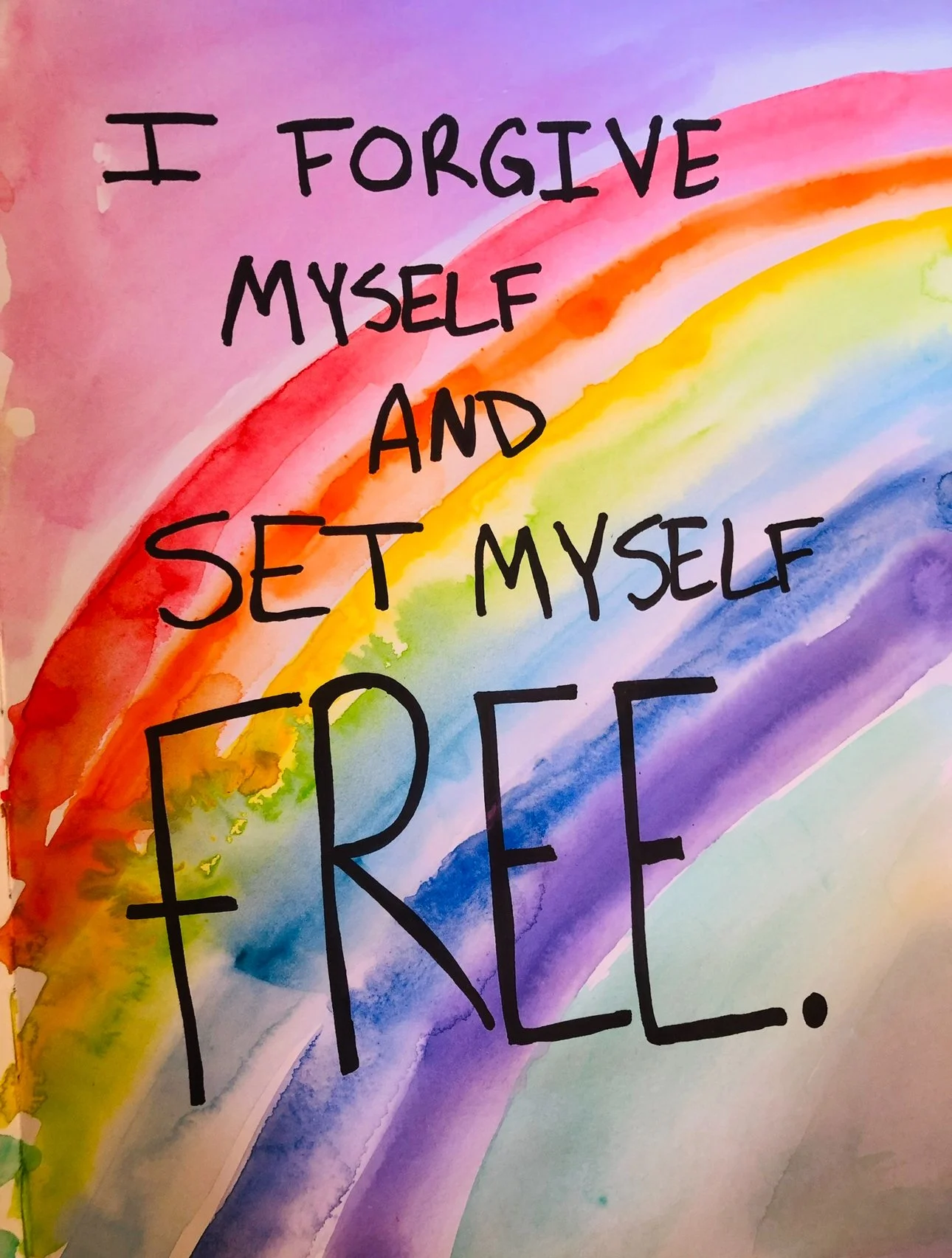 Colorful watercolor rainbow with the quote: "I FORGIVE MYSELF AND SET MYSELF FREE" written on it in black handwritten font.