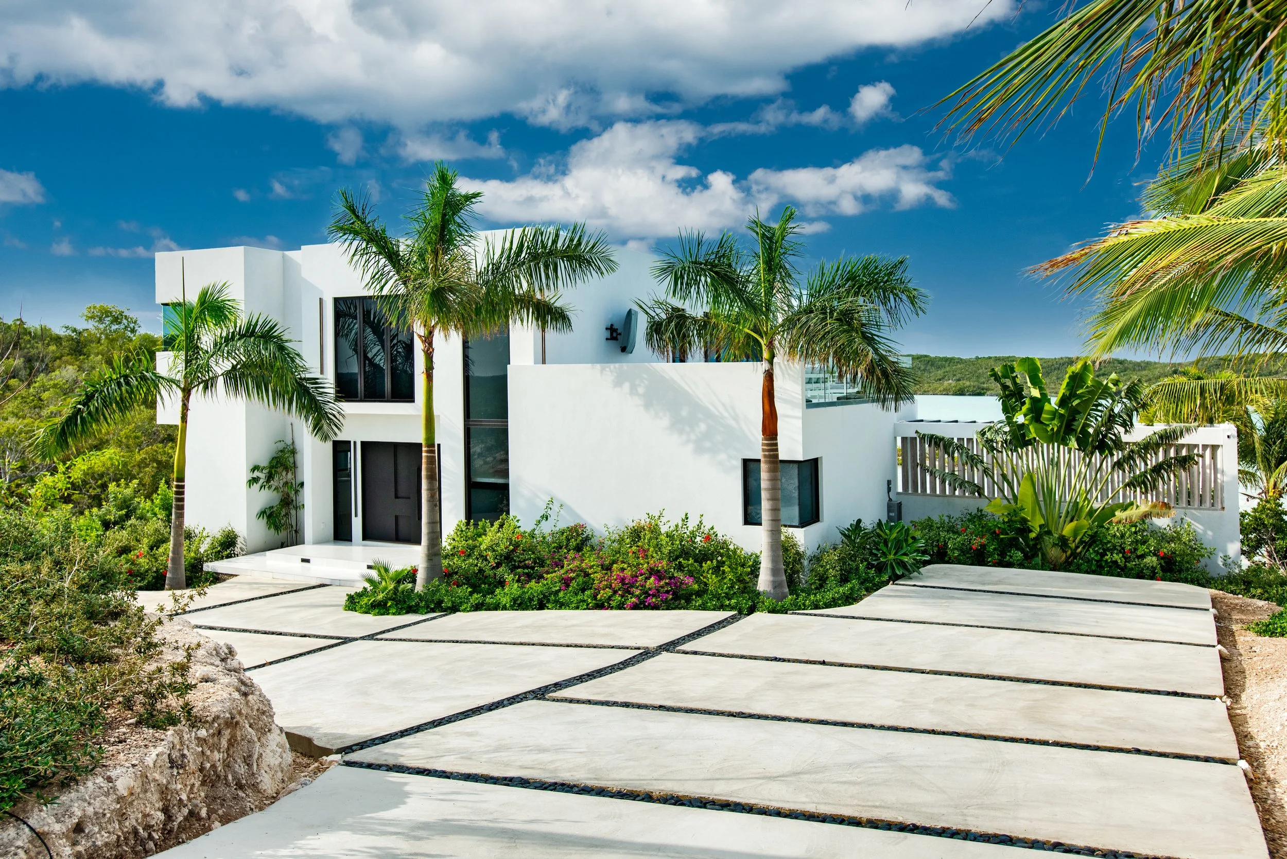 Modern white house with palm trees and landscaping in a sunny tropical setting
