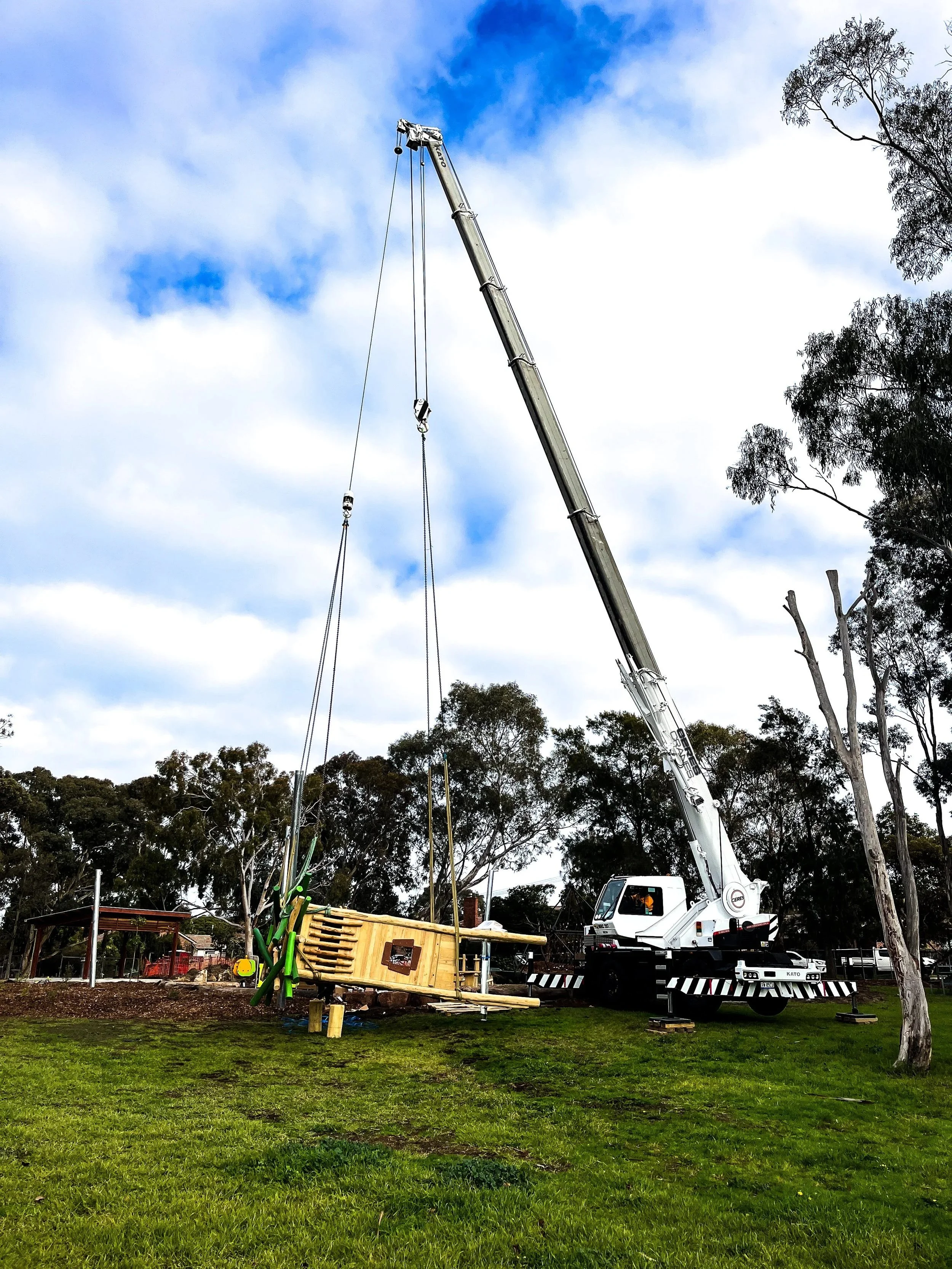 Crane lowering playground equipment into position in a park