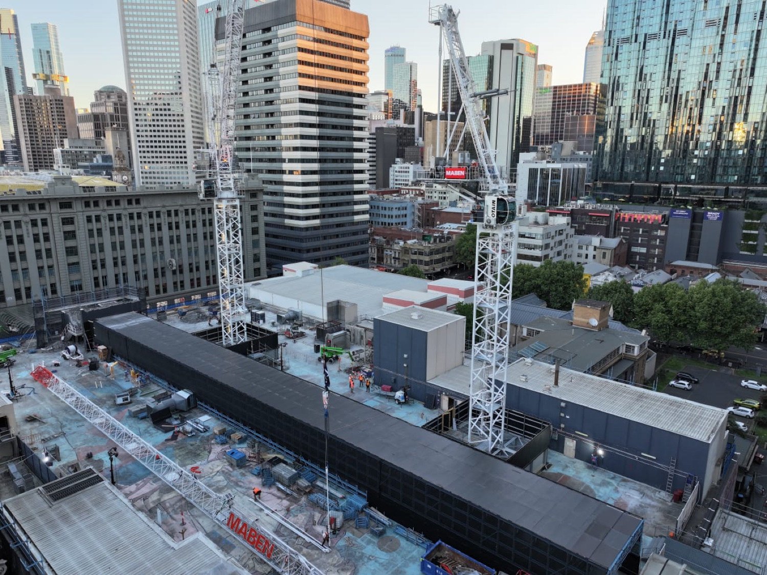 Two tower cranes rising from a rooftop building site in the Melbourne CBD