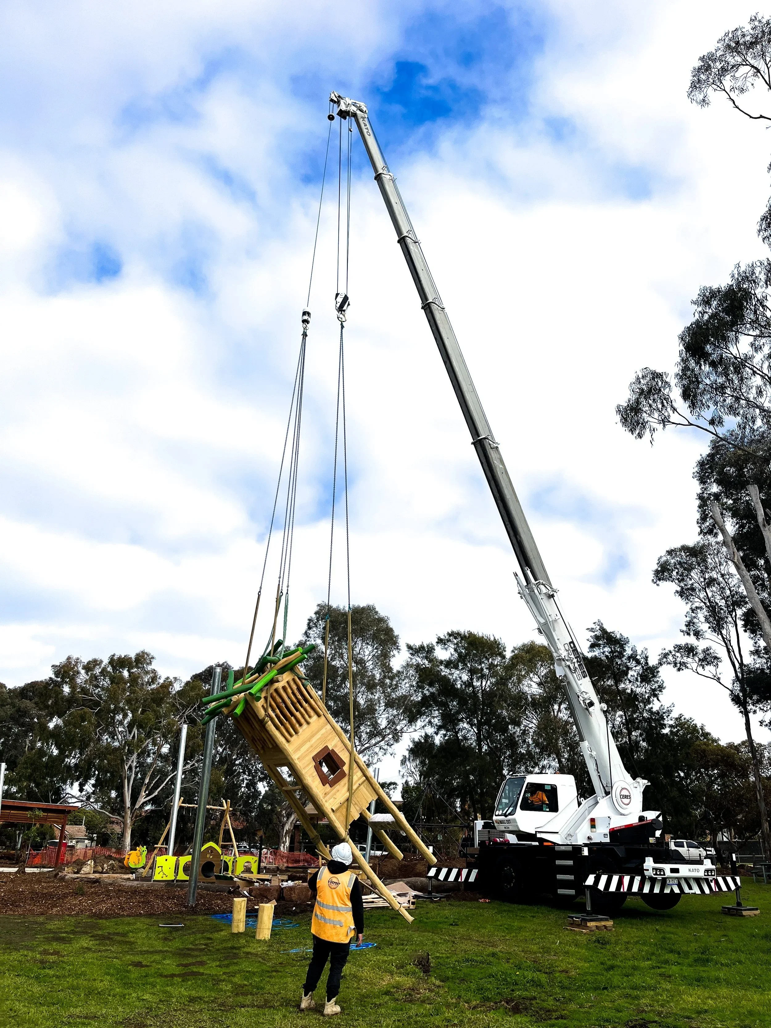 20T Kato city crane lifting playground equipment into place in a park