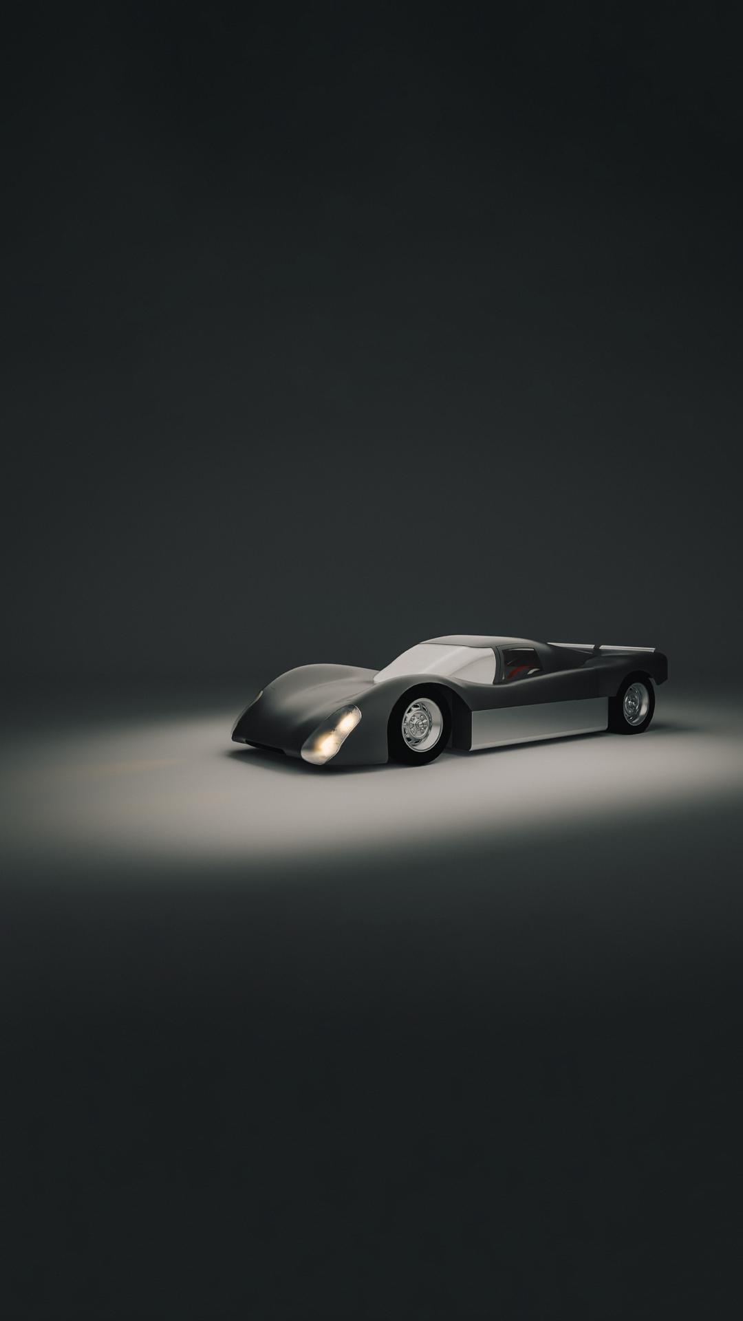 Ein vintage Rennwagen auf dunklem Hintergrund, beleuchtet, mit silberner und schwarzer Lackierung.