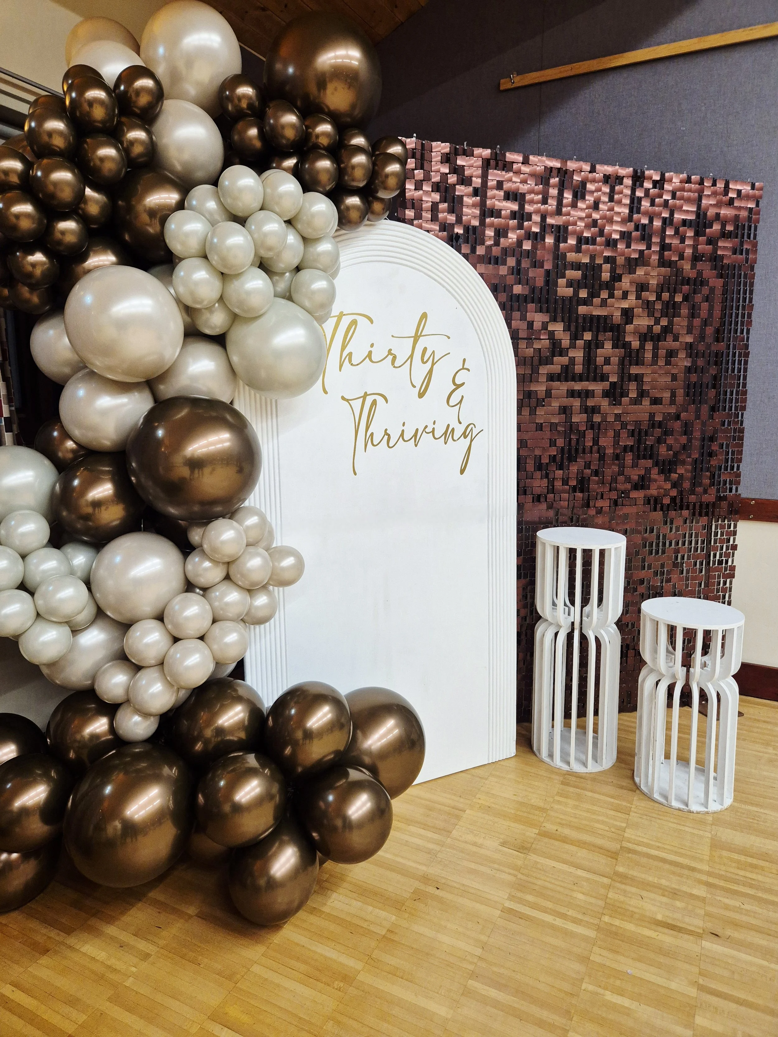 30th birthday backdrop styling with a luxurious cocoa sequin wal and balloons teamed up with personalised arched sailboard an plinths