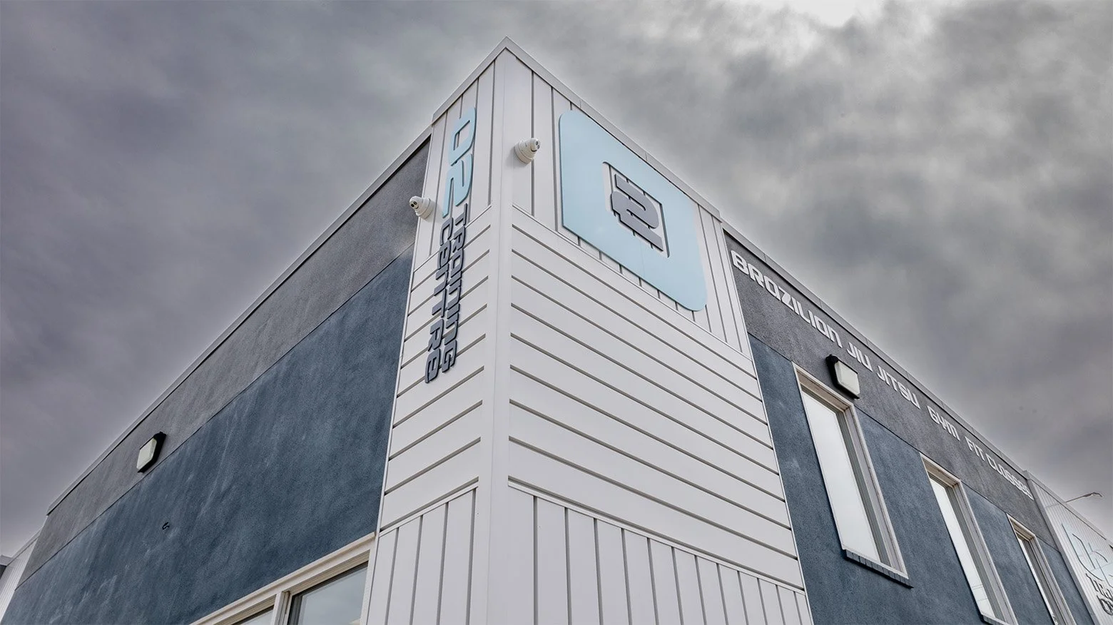 A modern commercial building with metal siding, featuring a logo of a speech bubble and business text on the corner.