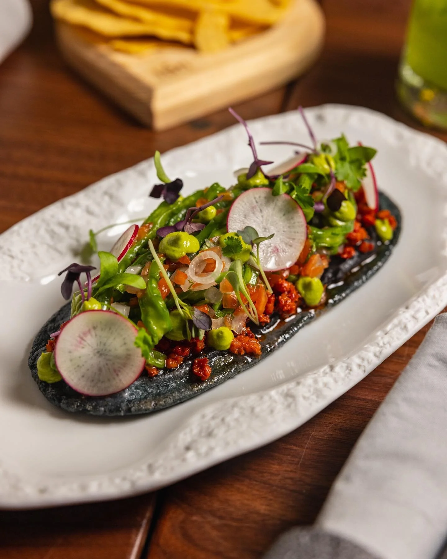On the table: Huarache, made with corn masa, black beans, mercado nopalitos, lettuce, avocado,  and queso fresco.