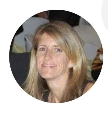 Portrait d'une femme avec des cheveux blonds, souriant, dans un environnement intérieur.