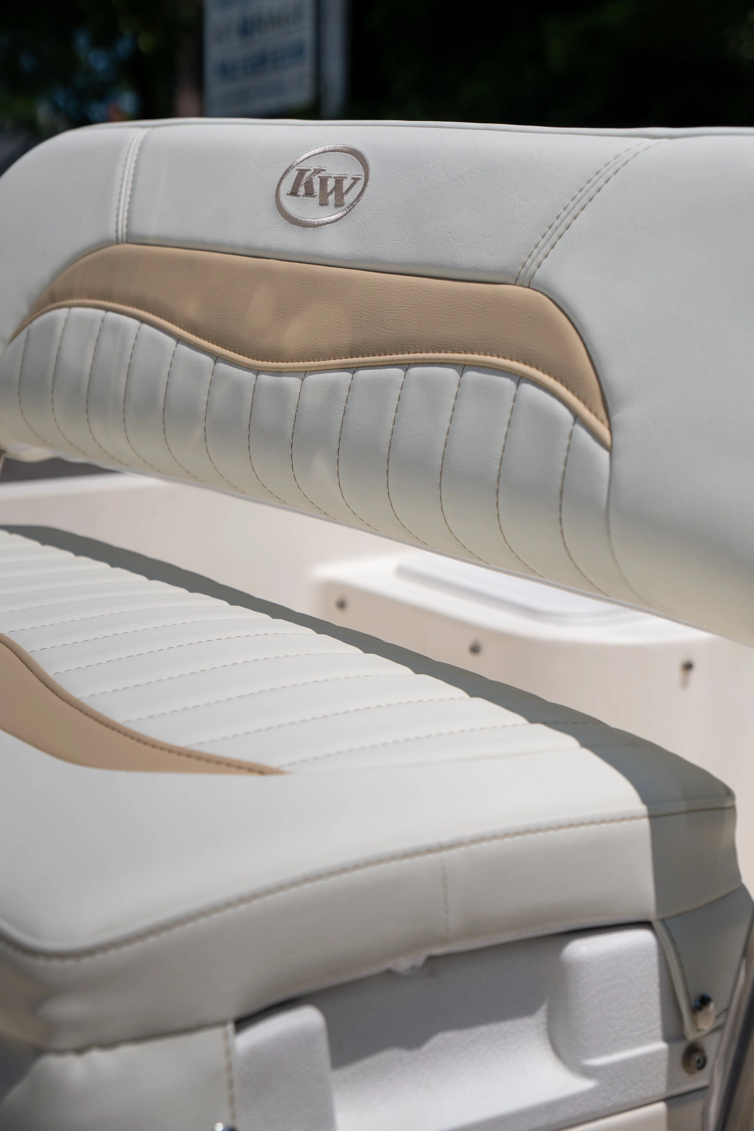 Close-up of a white boat seat with a beige accent and a branded logo 'KW' embroidered on the backrest.