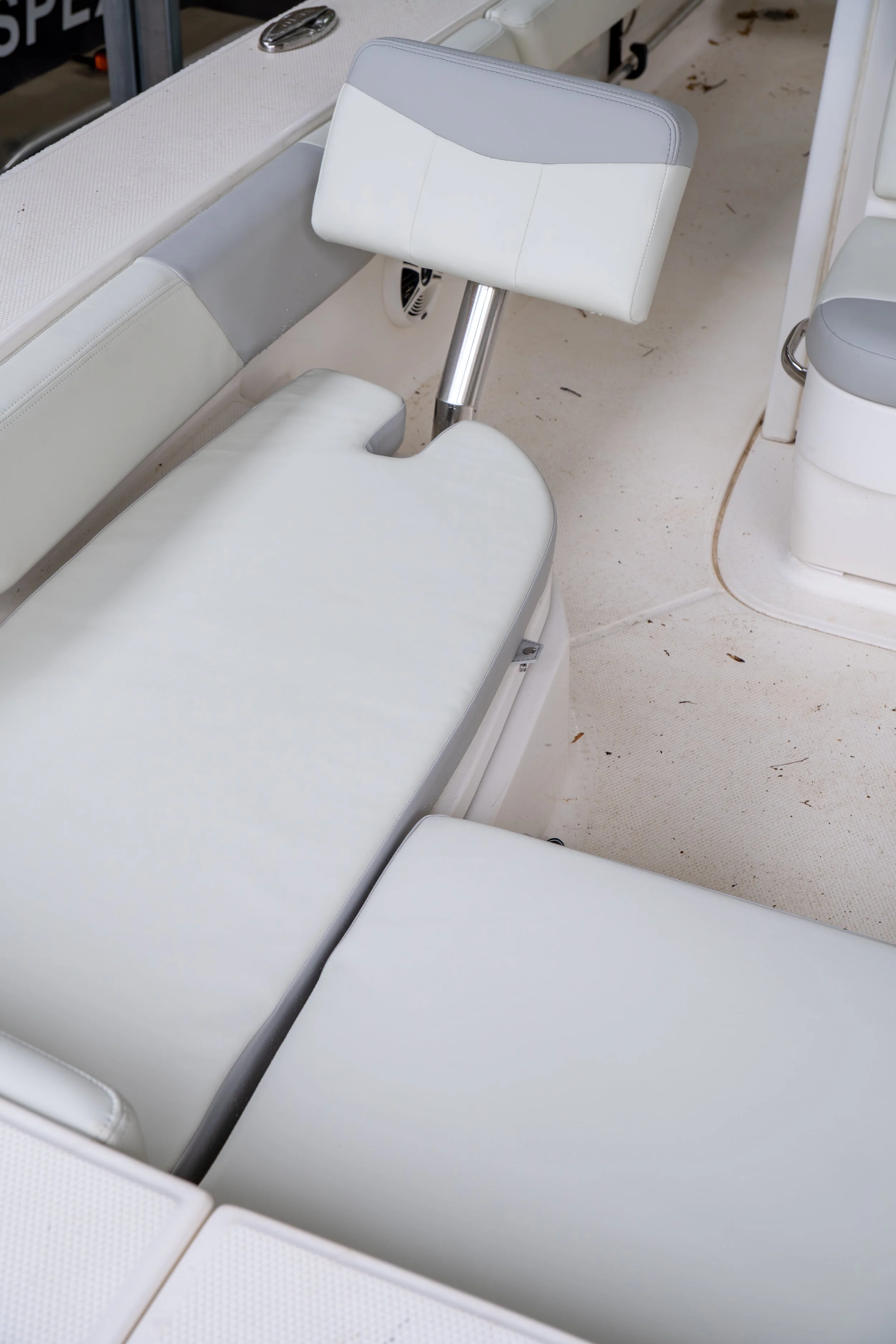 Close-up of white cushioned boat seats with a foldable swivel seat in the center.