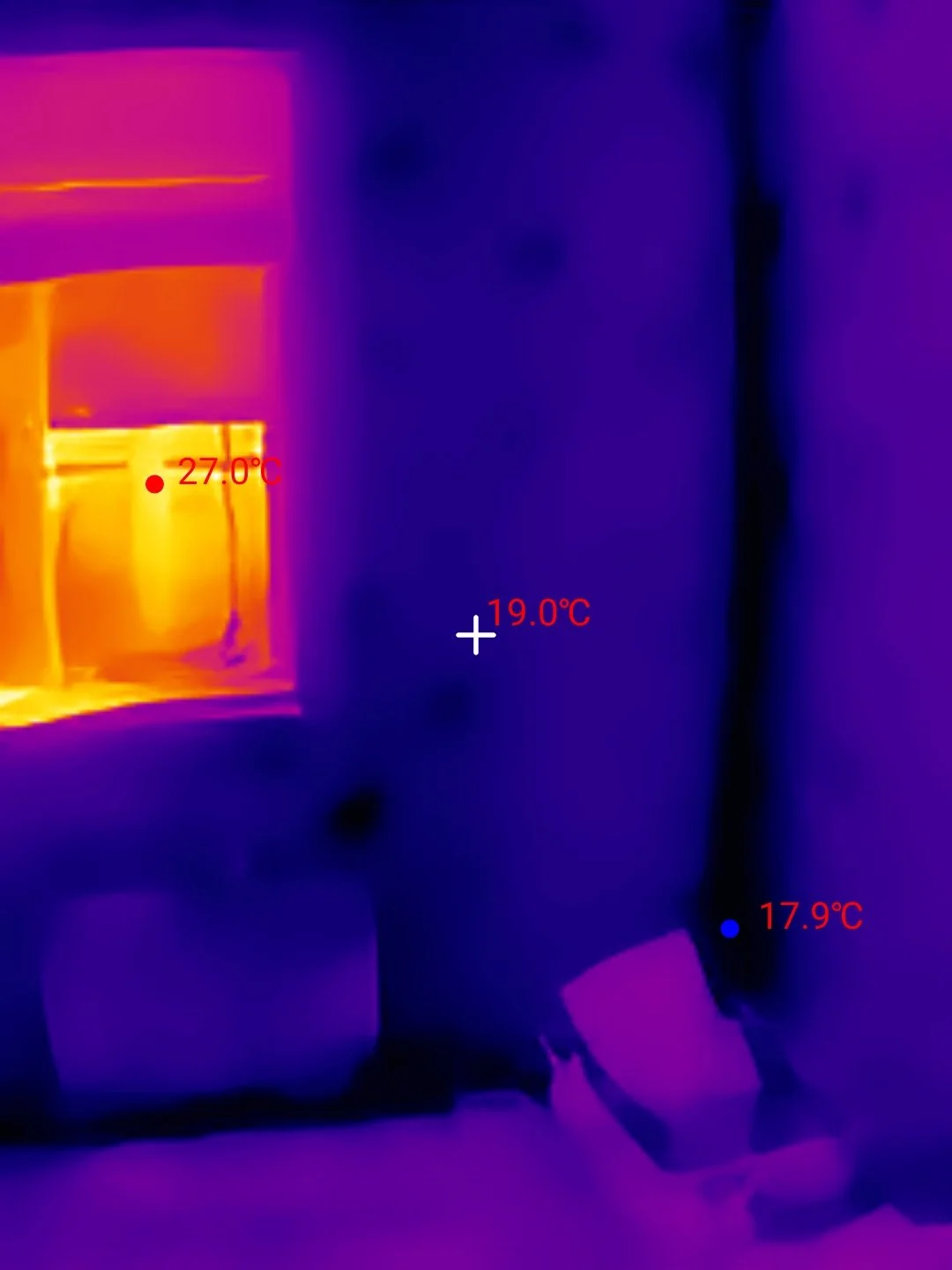 Thermal image showing temperature variation between window, wall and corner indicating heat loss and cold bridging