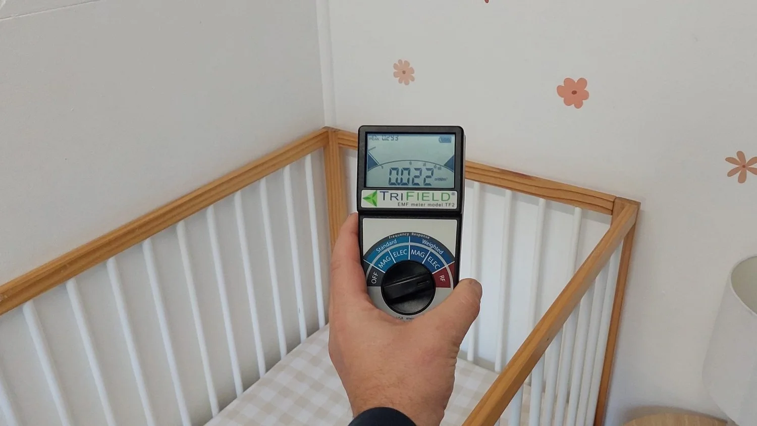 TriField TF2 meter held above a cot while a reading is recorded
