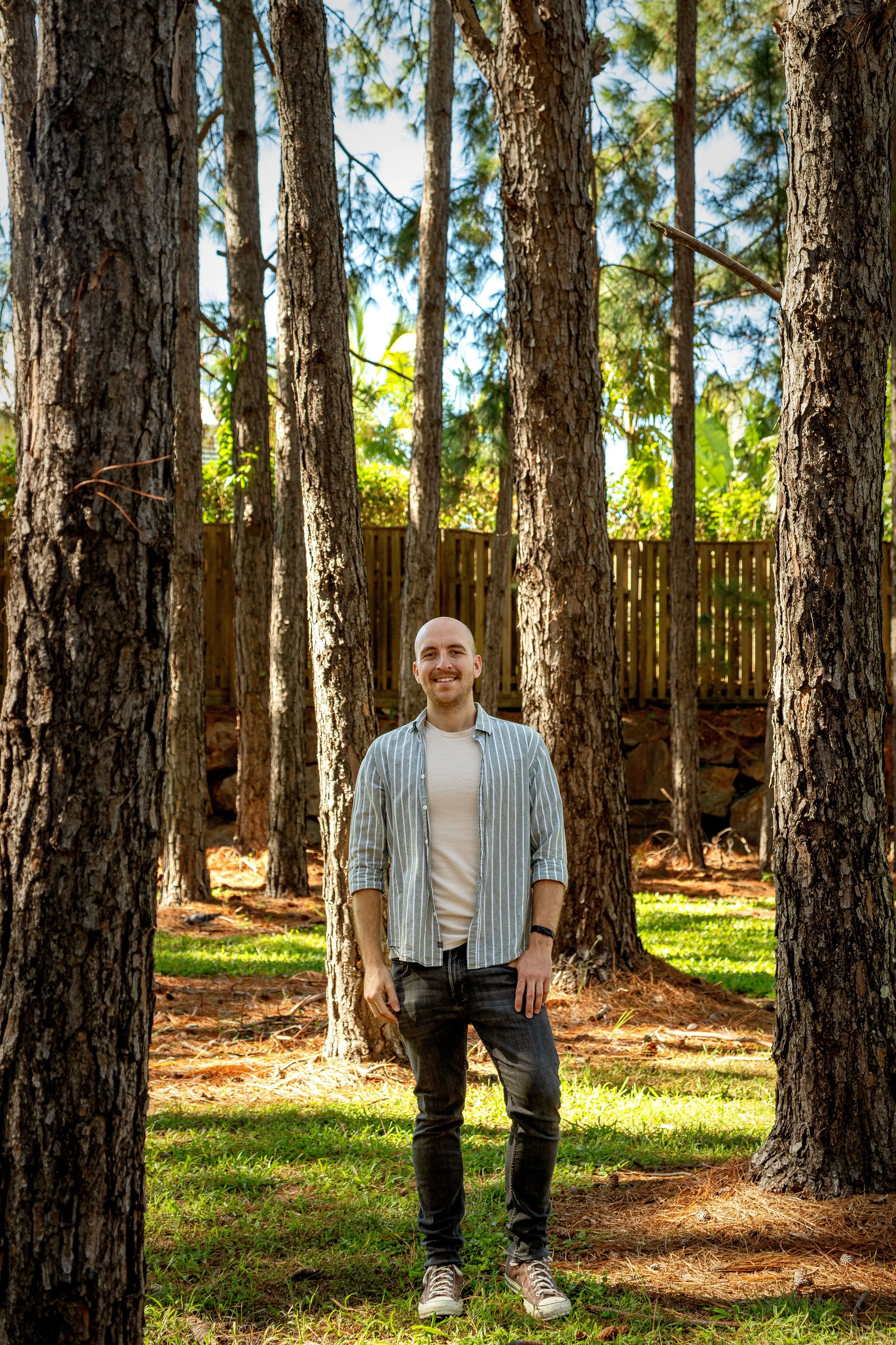 Natural dating portrait of man standing between trees in Coomera Waters backyard.