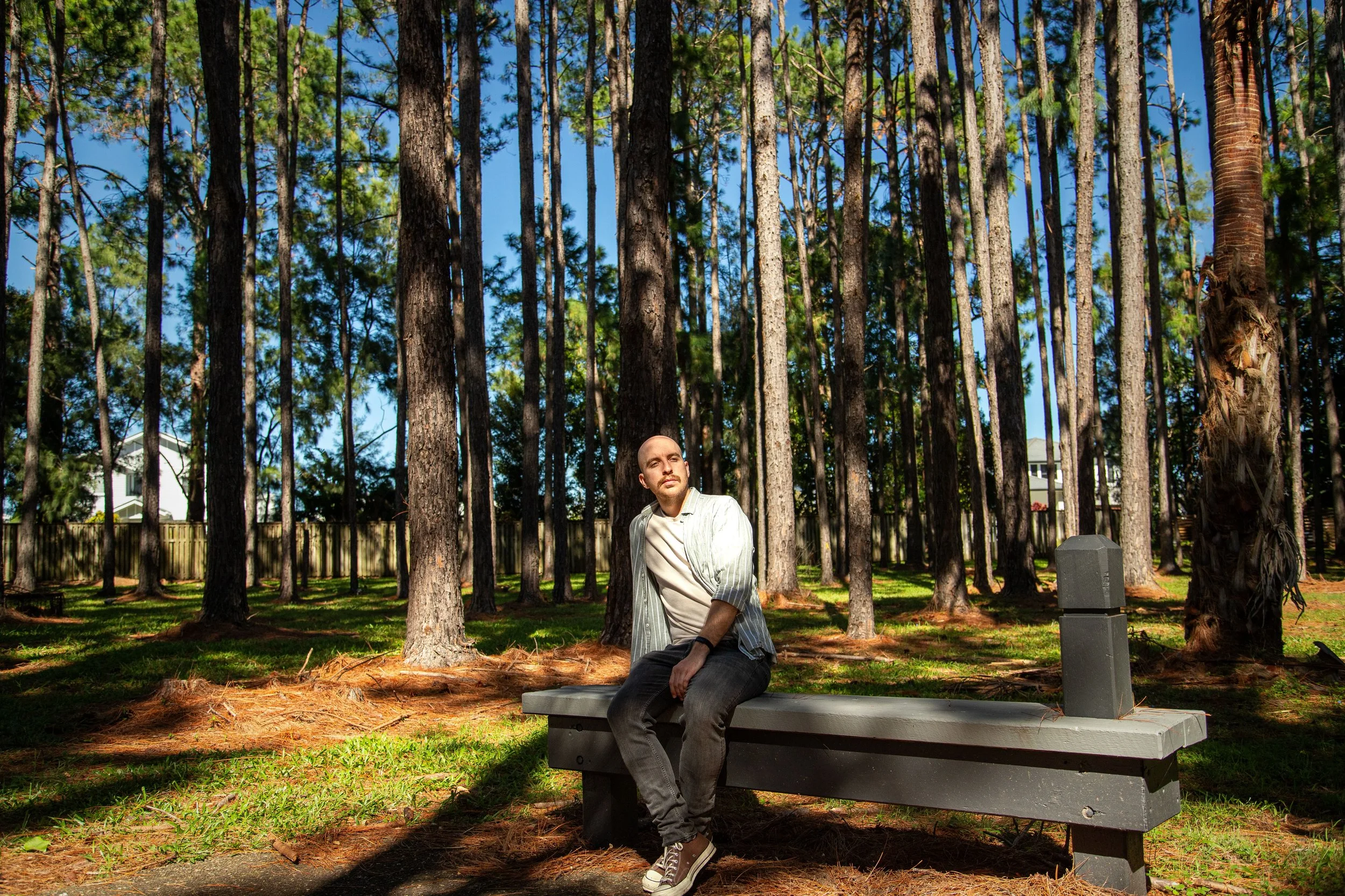 Man sitting on garden bench in pine forest setting, Coomera Waters.