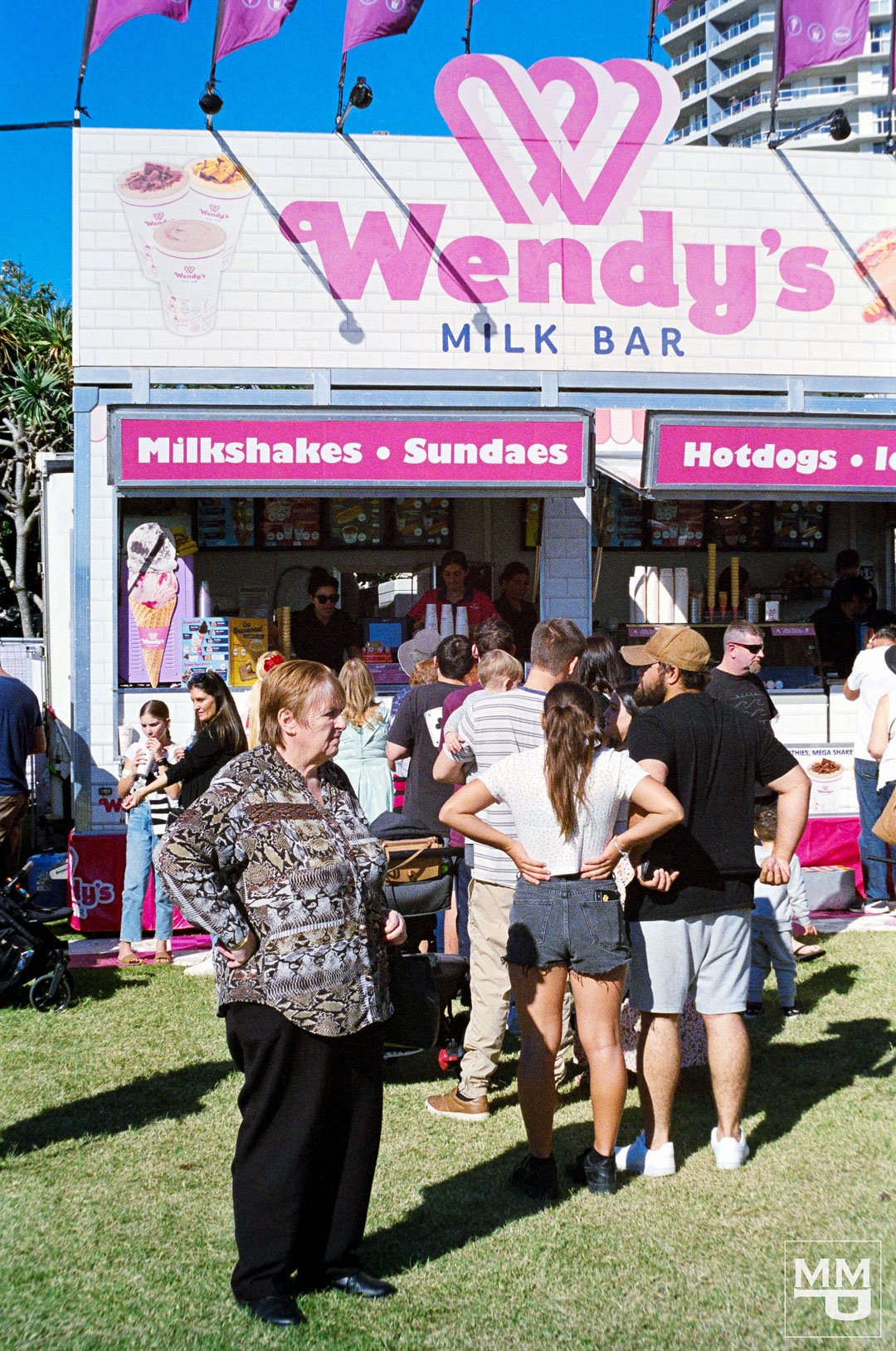 People waiting in line at a Wendy's Milk Bar truck.