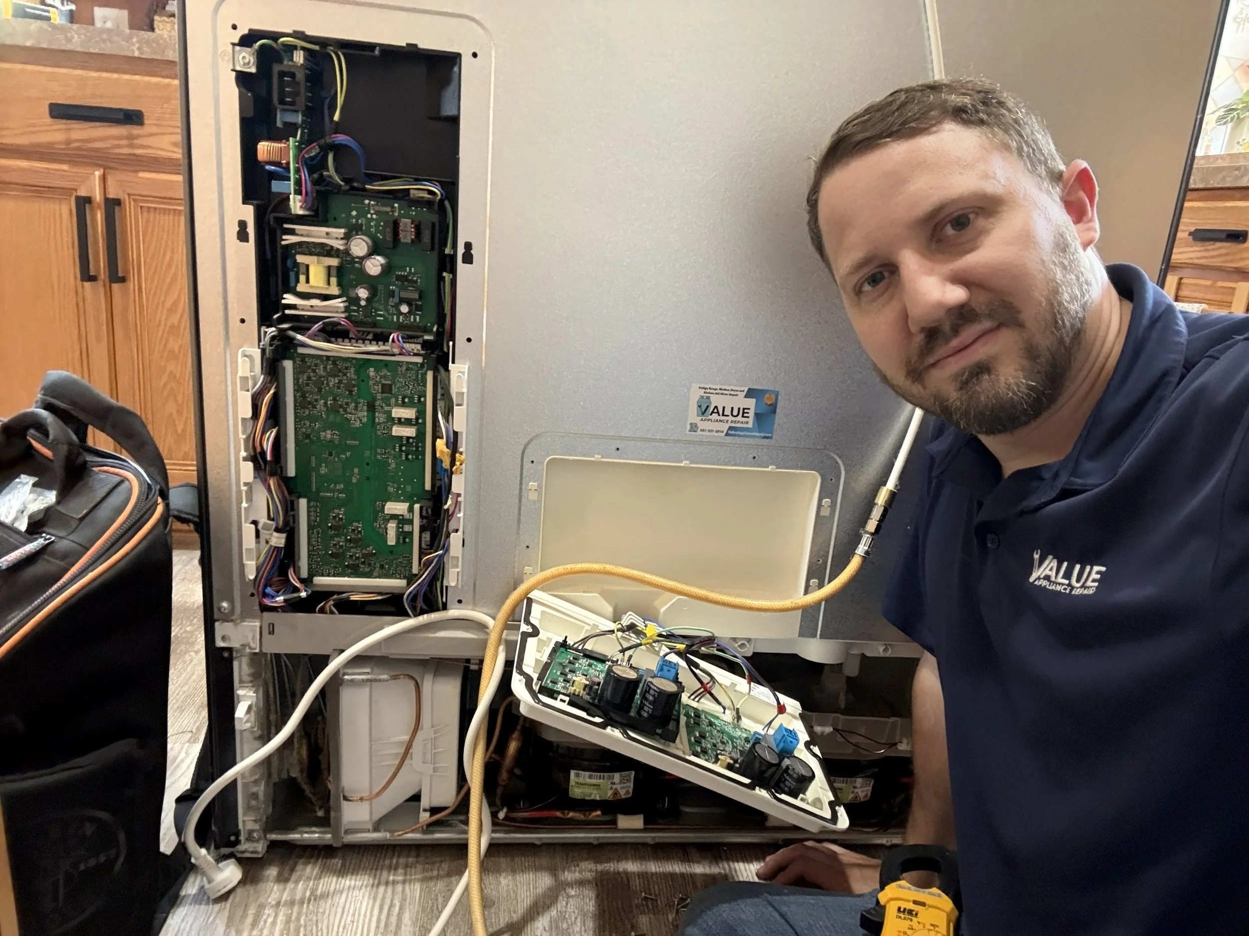 A man working on a refrigerator control board fridge not cooling repaired by a appliance tech in MN