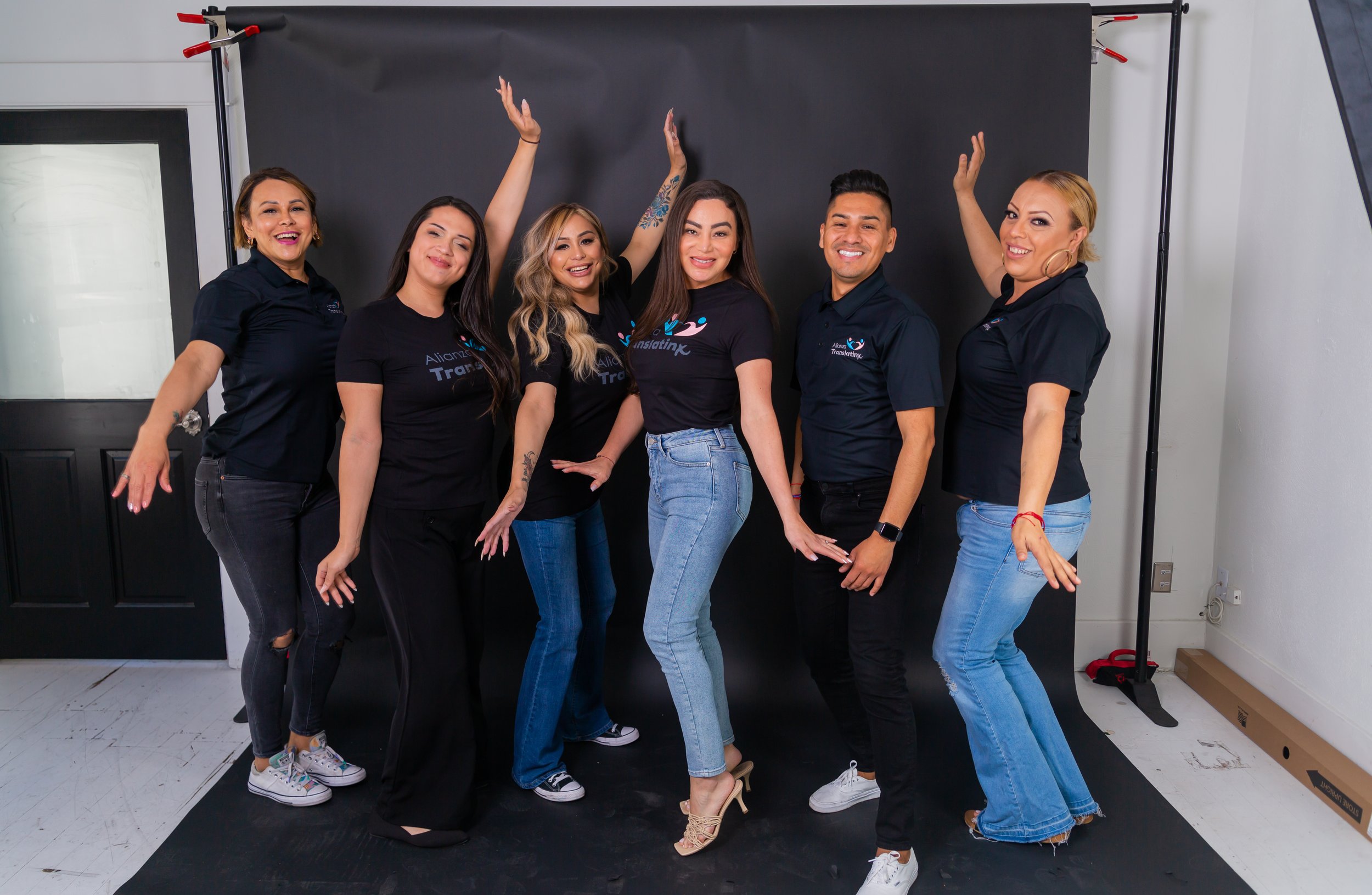 Staff posing for group photo with arms outstretched