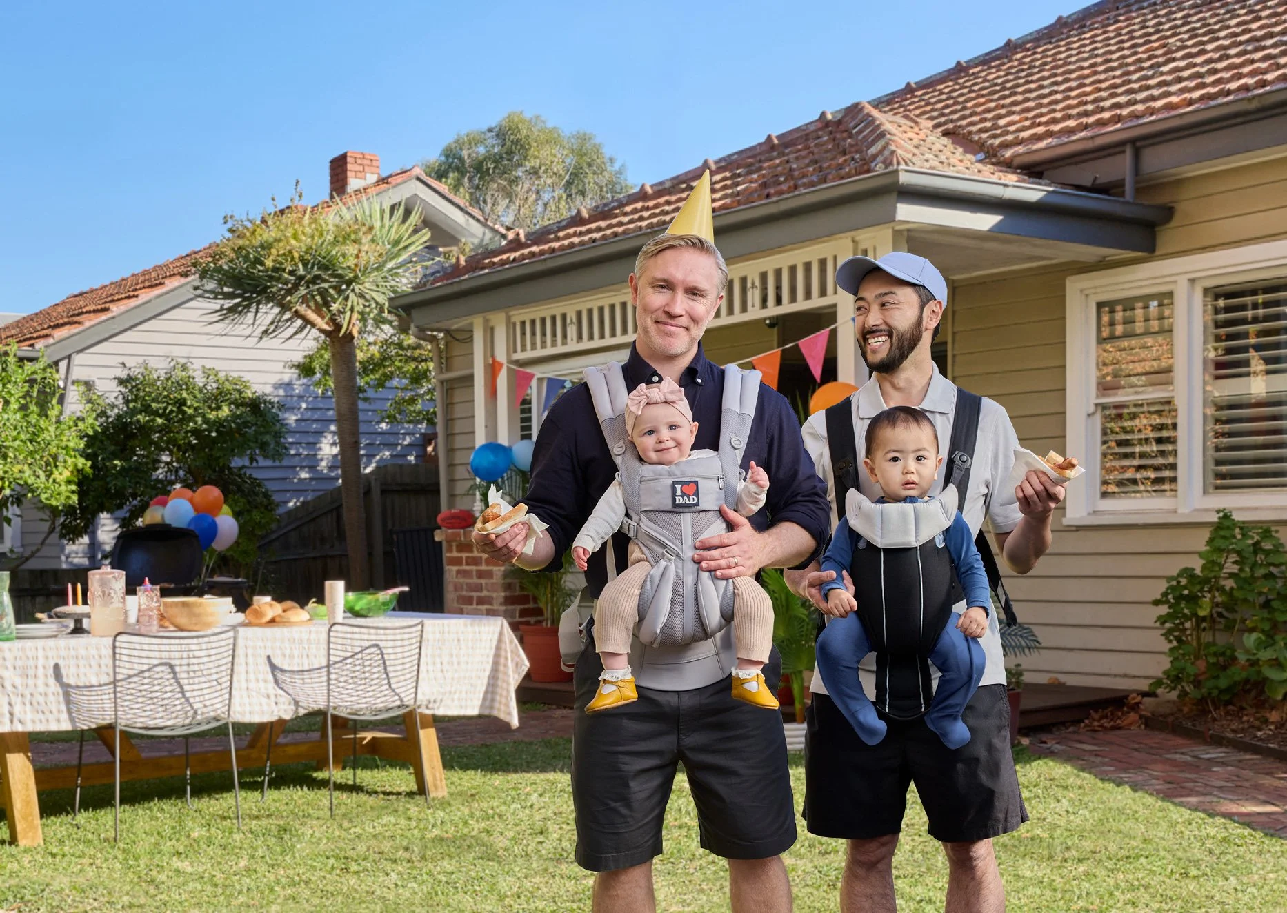 Two dads with their babies at a BBQ