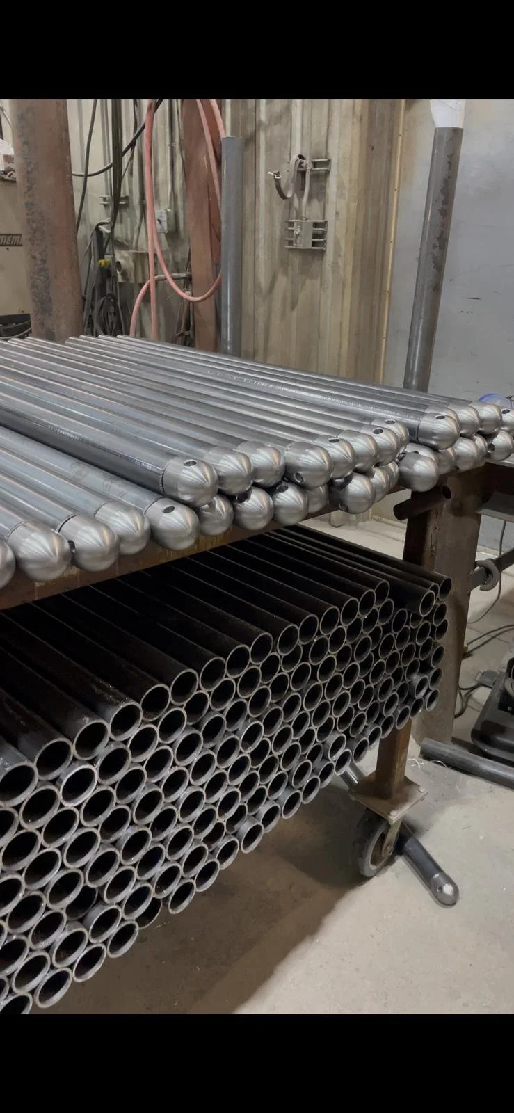 Custom steel tubes cut and fitted with rounded ends on a rack in the Klassen Repair Shop
