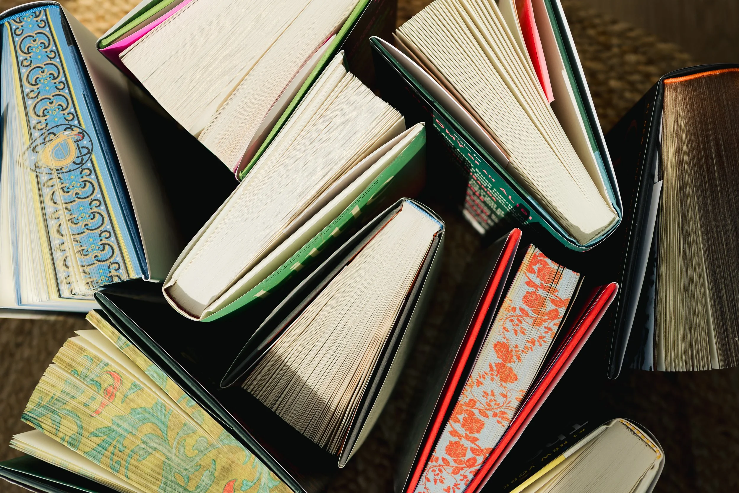 Top-down view of various open books arranged vertically on a table.