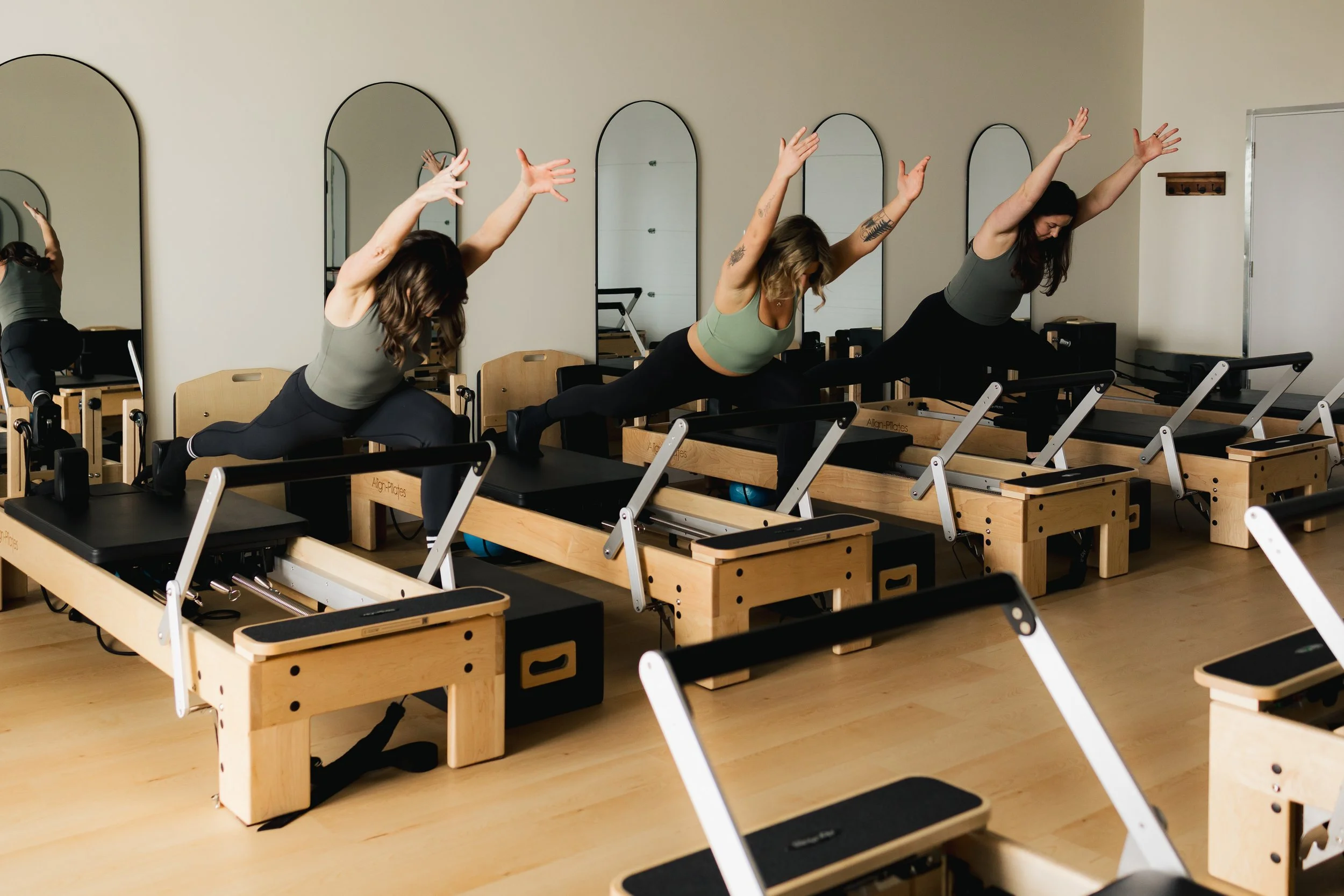 Women participating in a Pilates class using reformer machines in a studio.