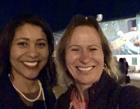 Two women smiling for a photo outdoors at night