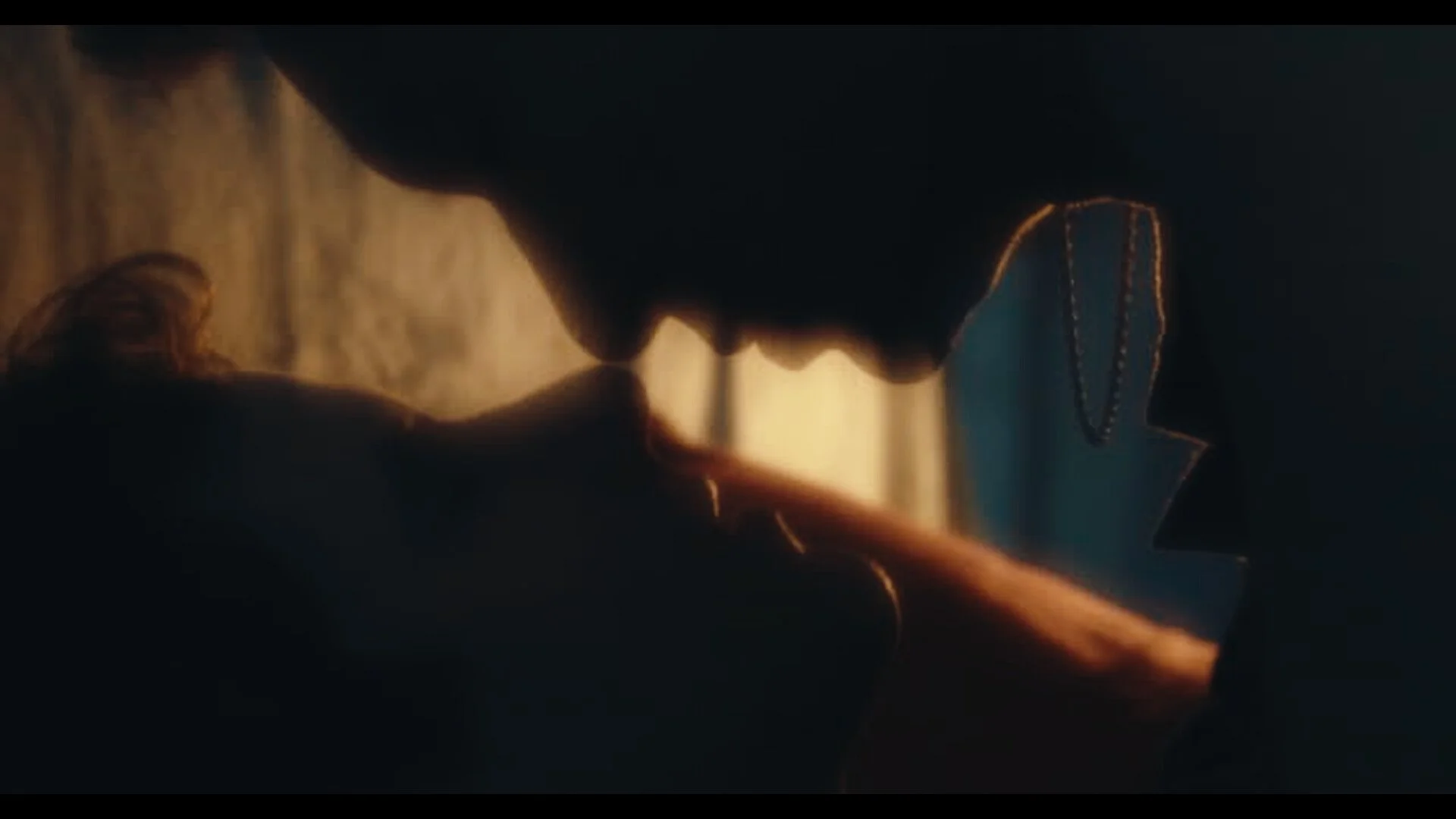 Close-up side profile of two people about to kiss, with warm lighting and blurred background.