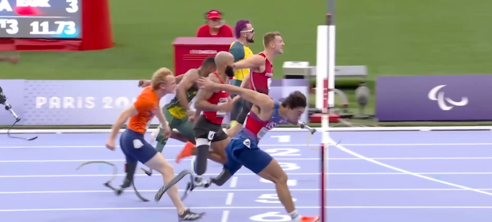 Paralympic athletes competing in a race on a blue track, with some running on prosthetic limbs.