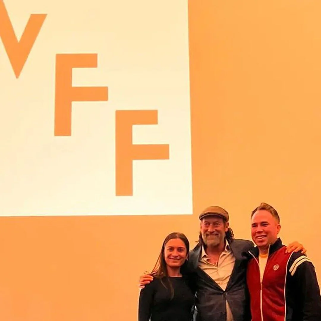 Three people standing in front of a screen displaying an eye chart with the letter 'F' in different sizes.