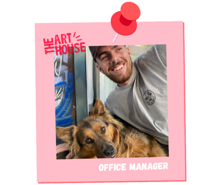 A cheerful man with a beard and a gray t-shirt smiling while holding a large, fluffy dog with brown and black fur. The photo is framed with a pink border, decorated with red pushpins, and has text that reads 'The Art House' in red and 'Office Manager' in white.