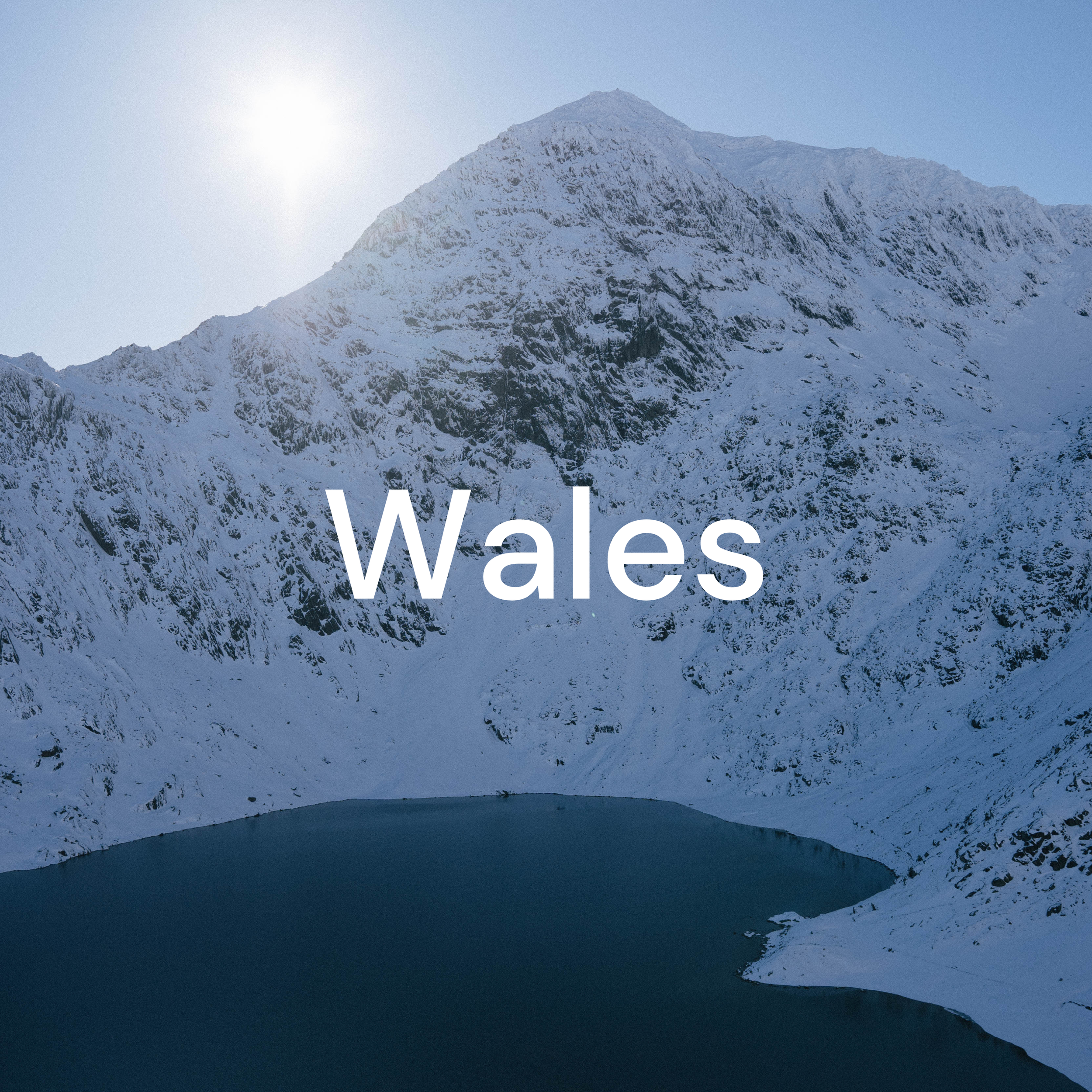 Snow-covered mountain with lake in the foreground and the word 'Wales' in the center.