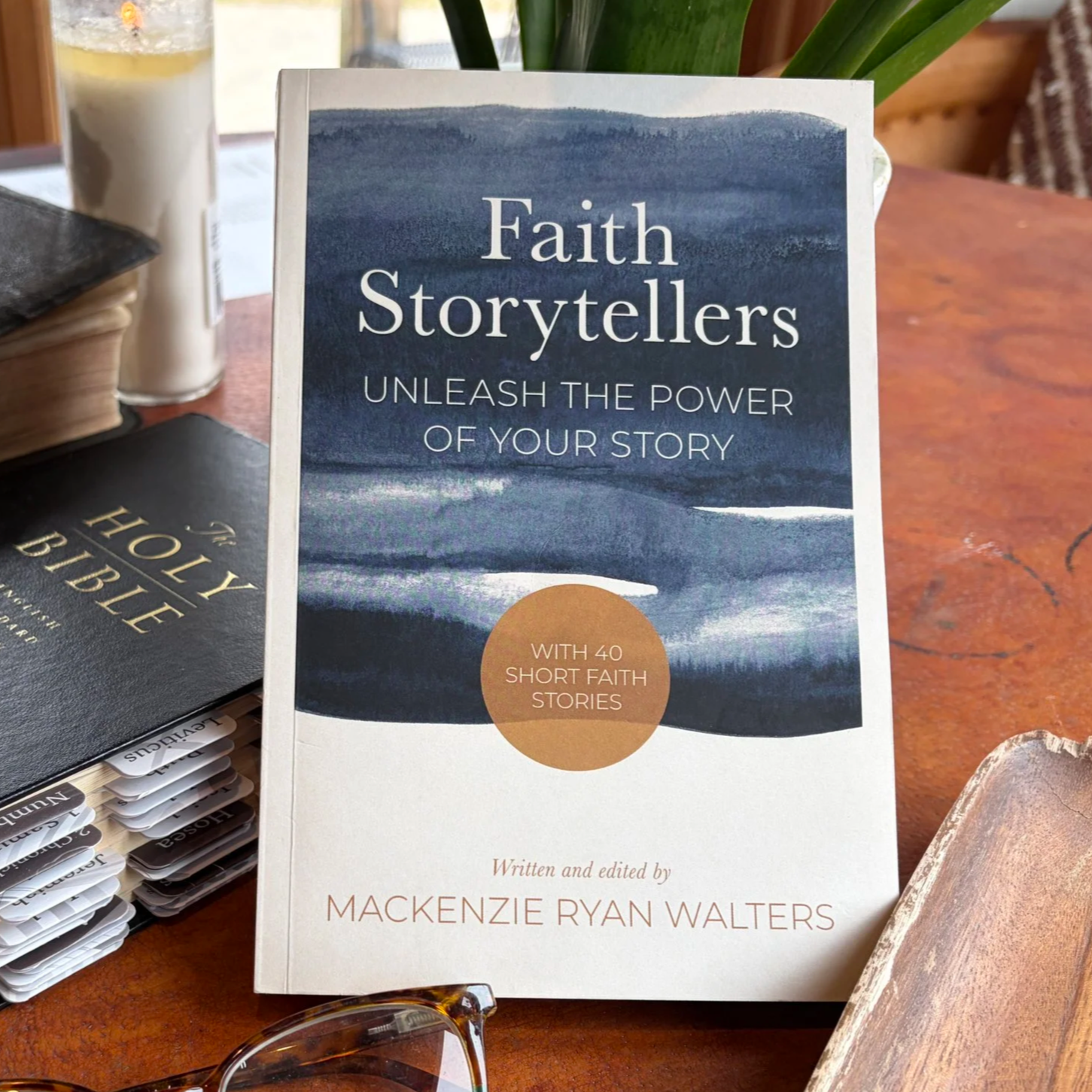 The "Faith Storytellers: Unleash the Power of Your Story" is displayed on a table next to the Holy Bible. It's the best guide on testimony writing and includes 40 short faith stories as examples. Buy this book for testimony sharing tips and tools.