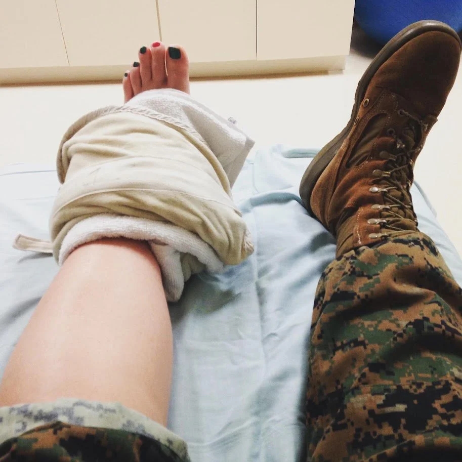 U.S. Marine Brittany Taga injured leg her leg, it’s pictured here wrapped in a towel. Her injured leg has painted toenails besides her combat boot, illustrating vulnerability and humility in the faith story "God gives grace to the humble"