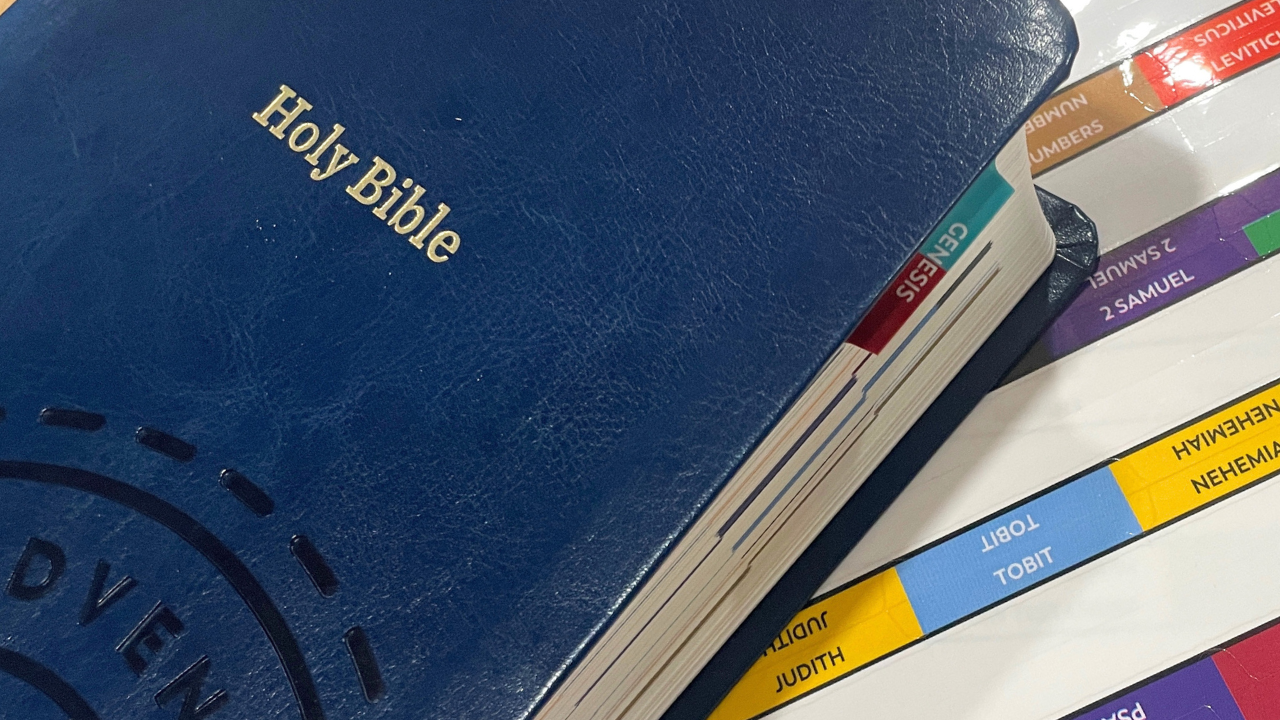 Great Adventure Catholic Bible Indexing Tabs are next to the the Holy Bible. The book of Genesis has a tab in place in this image.