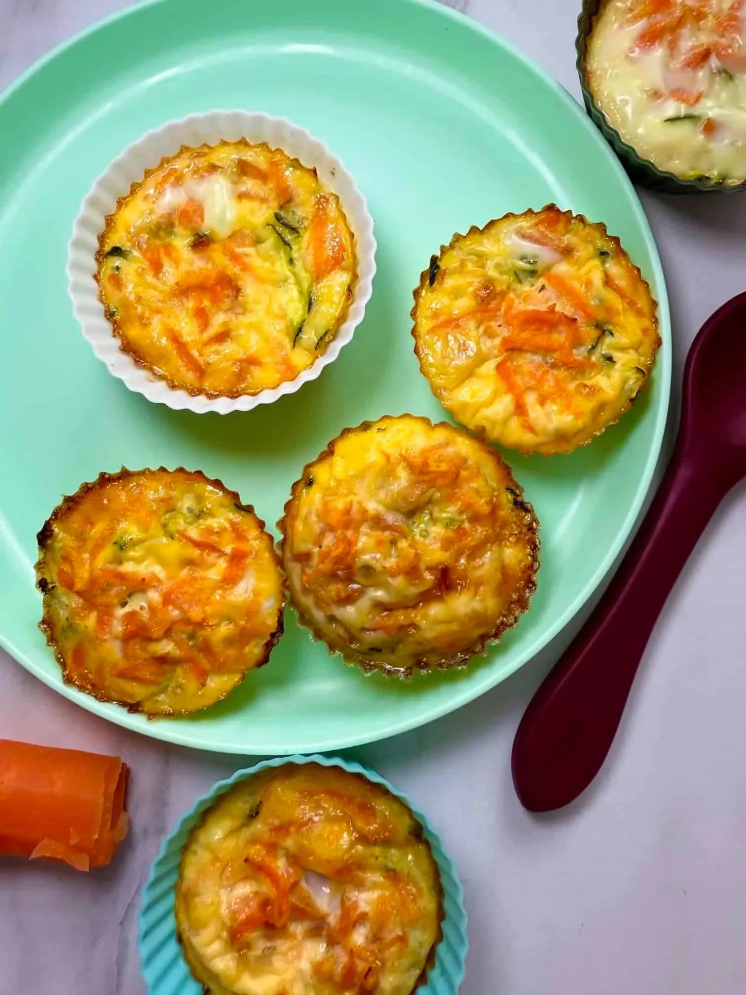 Four baked egg muffins in silicone cases on toddler plate
