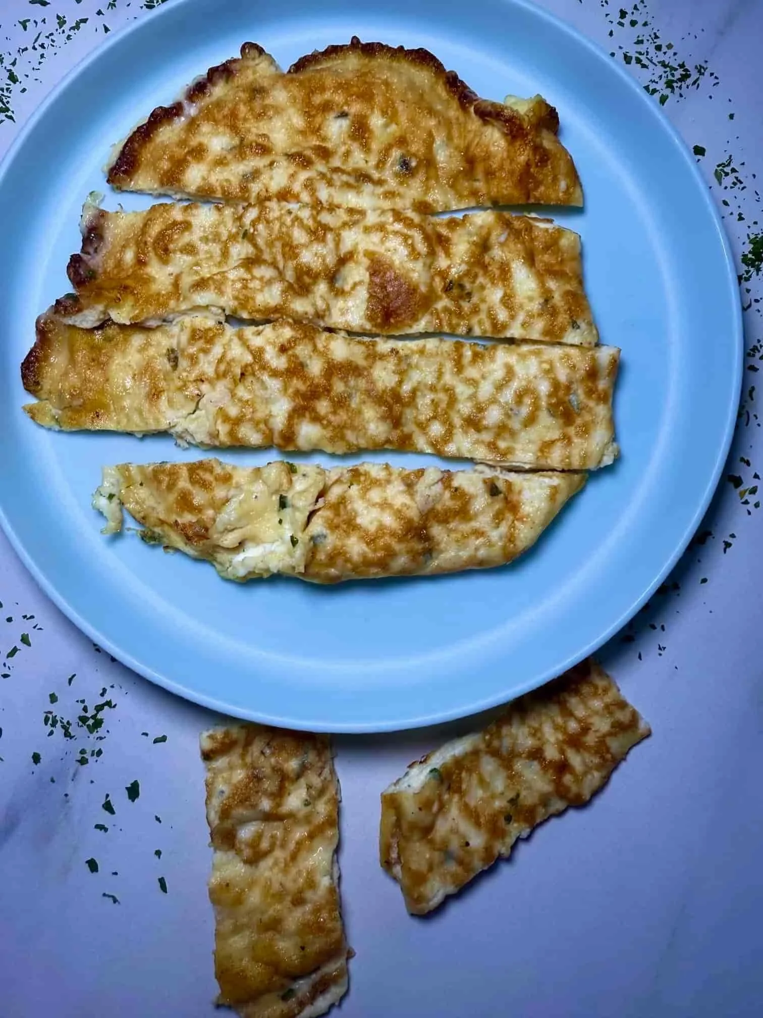 A cooked cottage cheese omlette served on toddler plate and cut into manageable slices