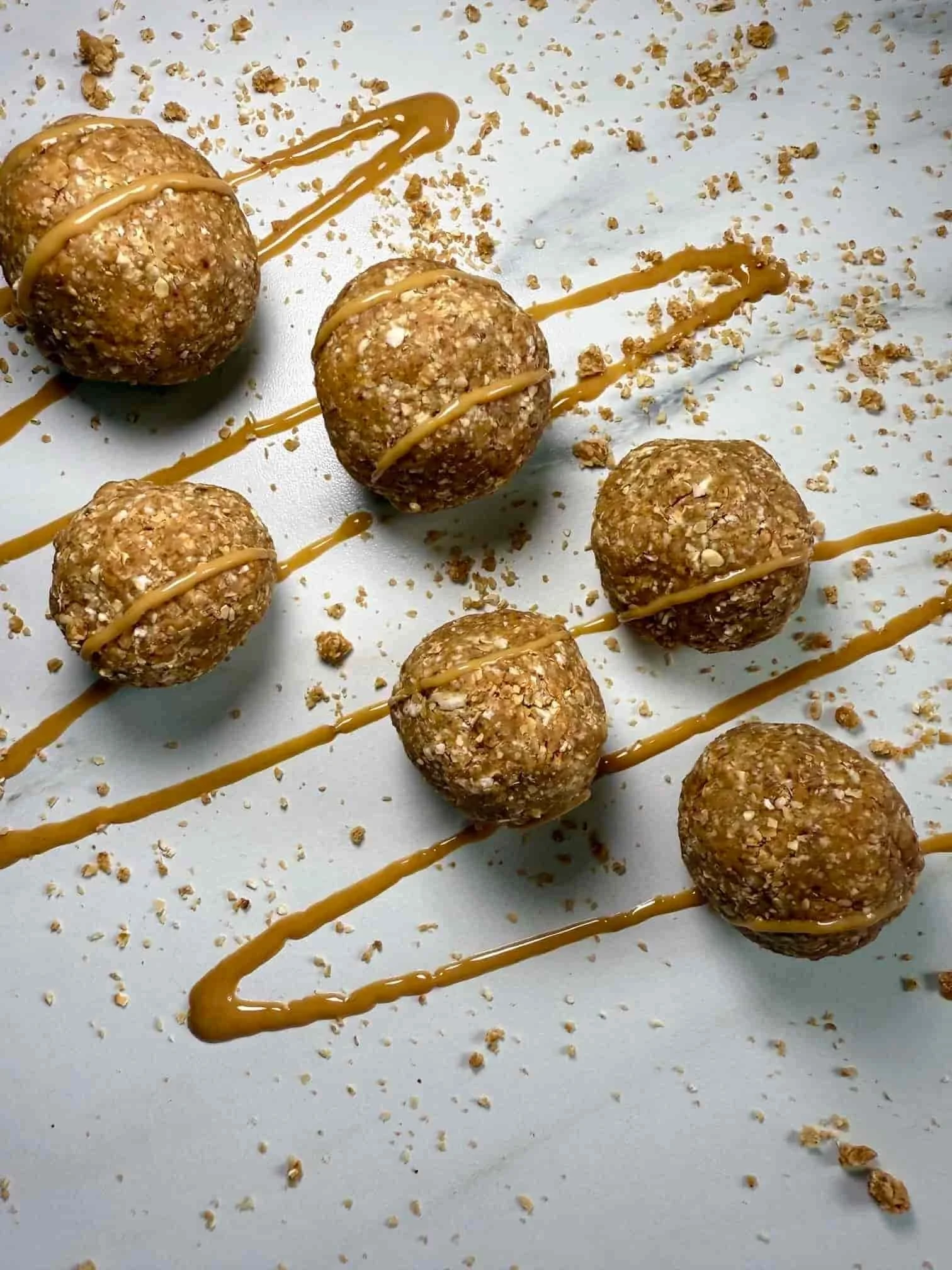 Several oat, date and peanut butter balls topped with peanut butter on serving board