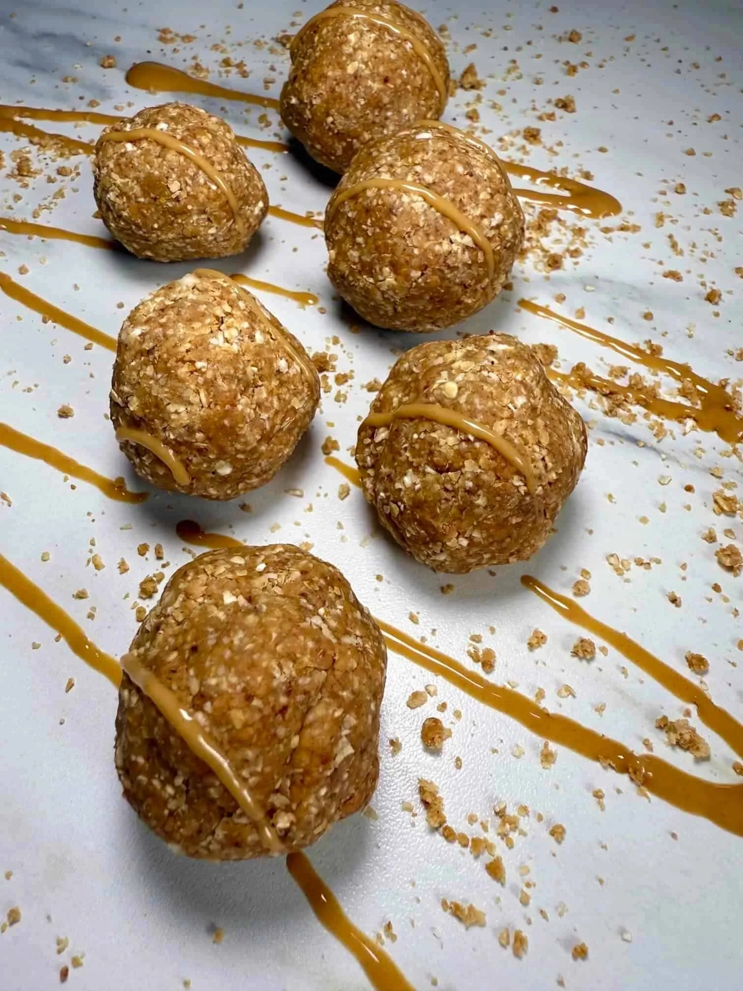 Several oat, date and peanut butter balls topped with peanut butter on serving board