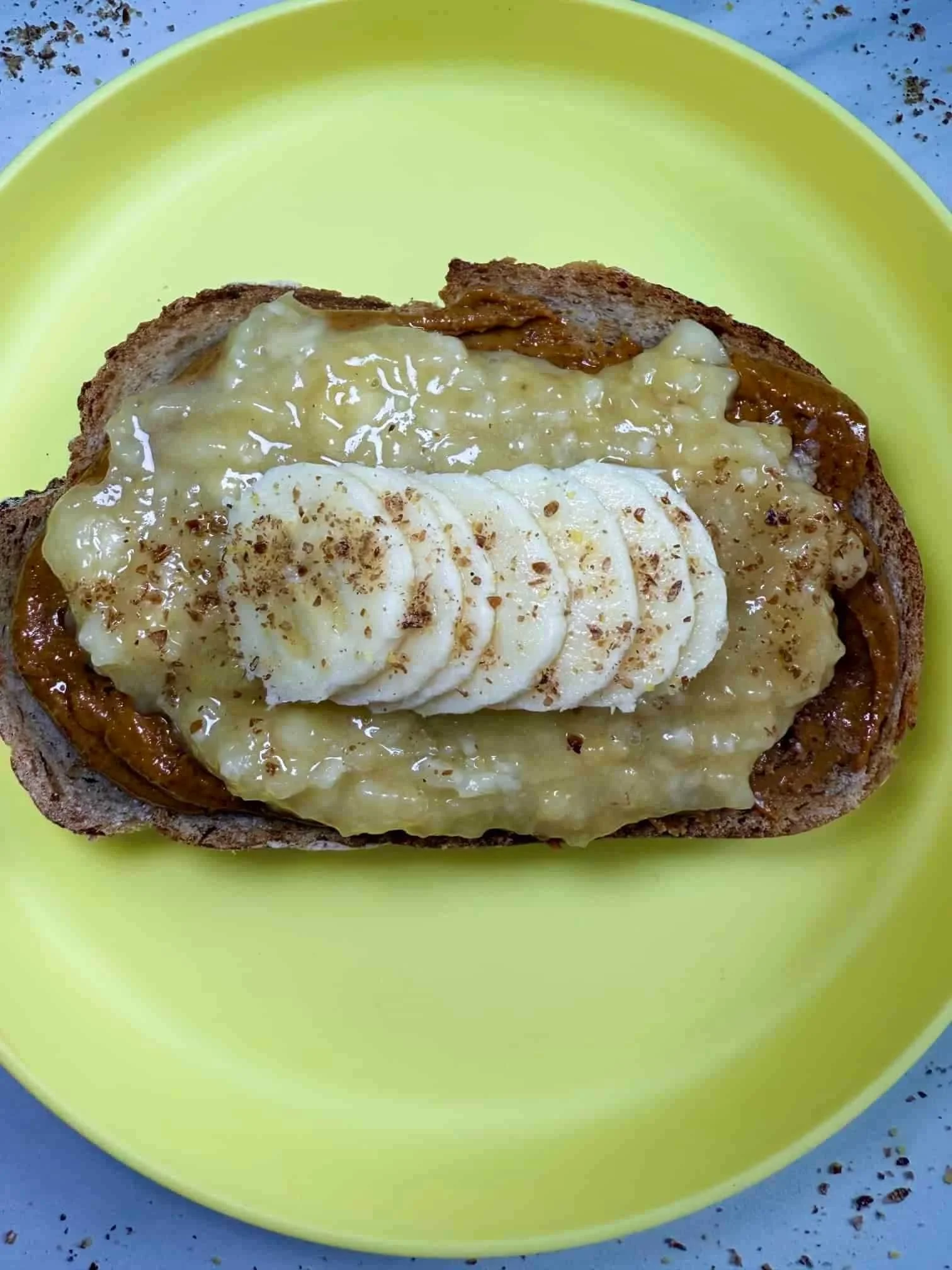 A slice of toast layered with peanut butter, pureed and sliced banana and sprinkled with flaxseed