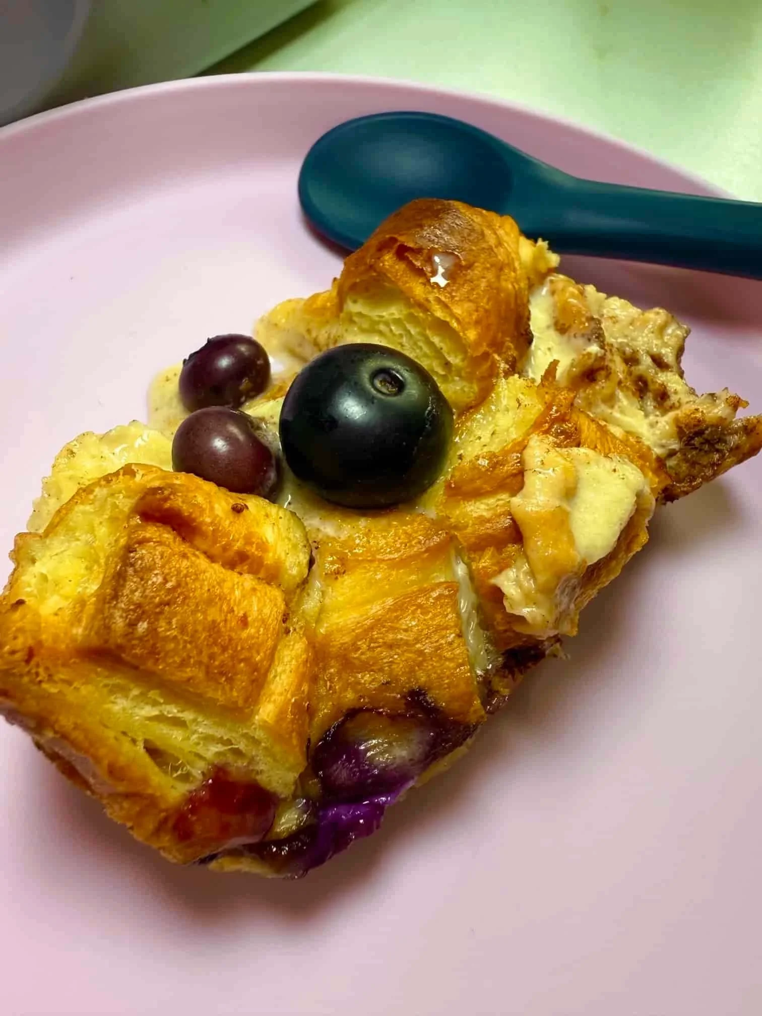 Close up image of a cooked slice of blueberry croissant breakfast bake