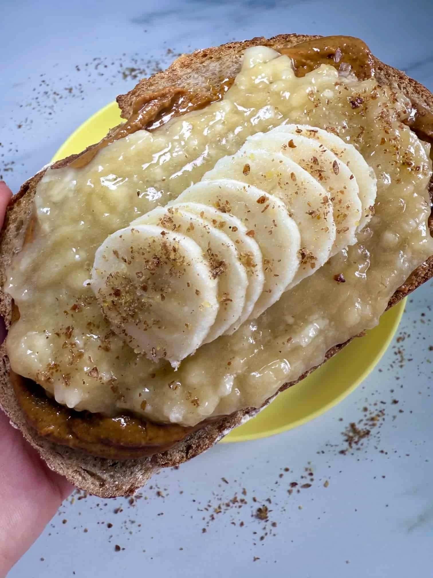 A slice of toast layered with peanut butter, pureed and sliced banana and sprinkled with flaxseed