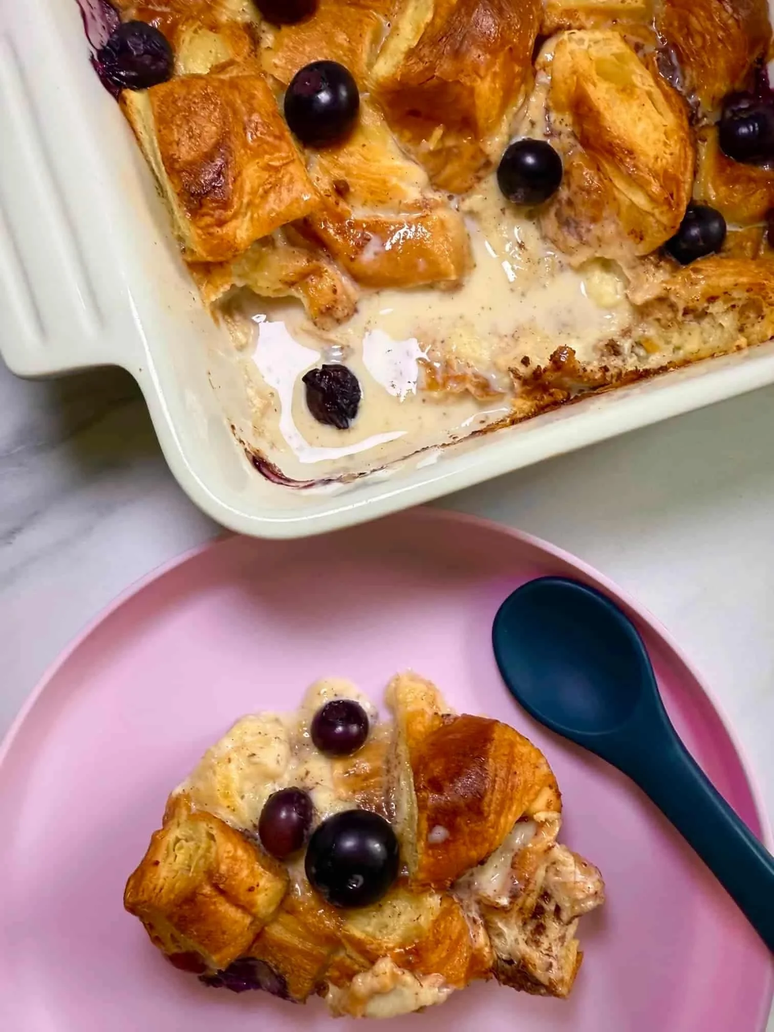 Close up image of the baked blueberry croissant breakfast bake together with one serving on a toddler plate
