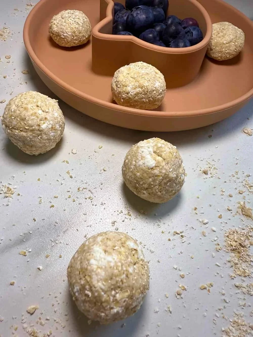 Cottage cheese and oat balls served with blueberries on a toddler plate