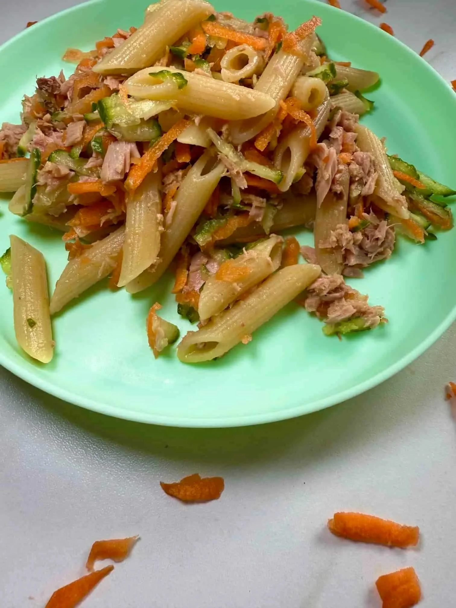 A toddler sized portion of tuna pasta salad with carrot and cucumber