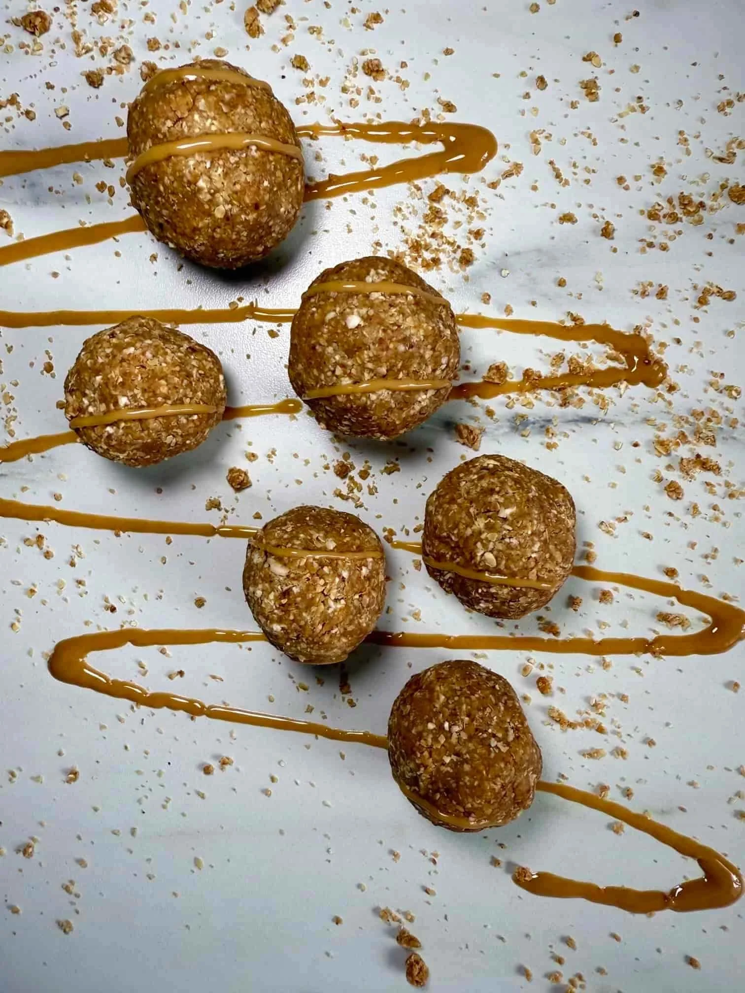 Several oat, date and peanut butter balls topped with peanut butter on serving board