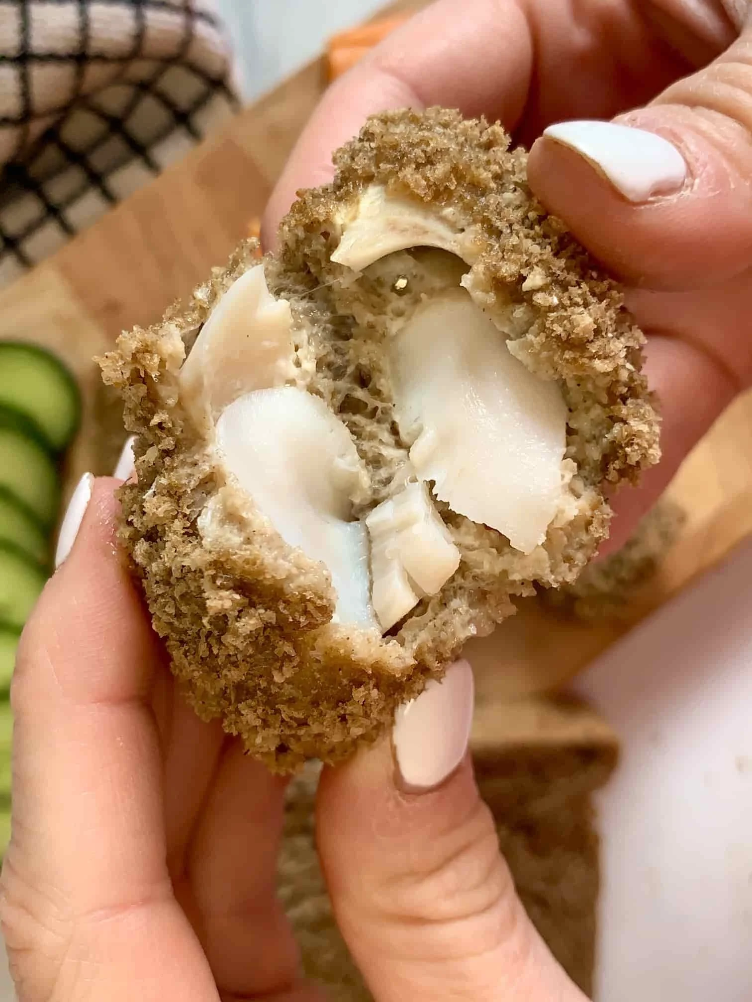 A close up image of a homemade breadcrumbed white fish finger broken in half to reveal the flaked fish