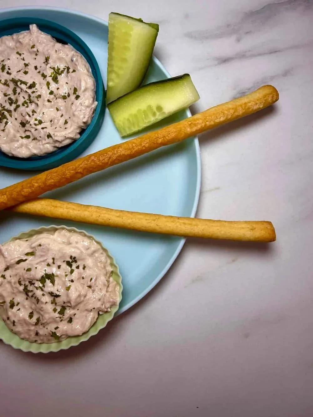 Cream cheese and tuna dip served in silicone case with breadsticks and sticks of cucumber