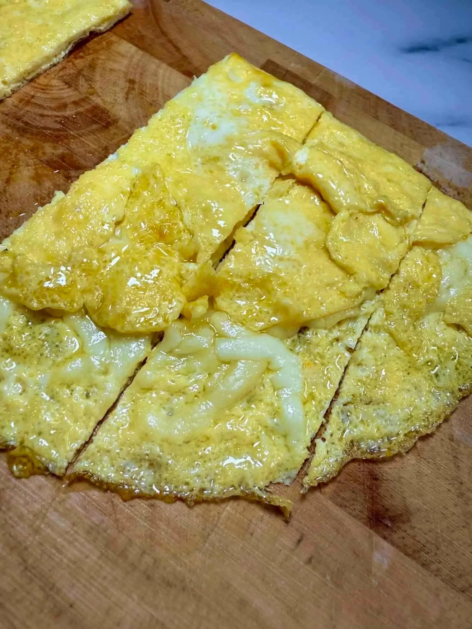 Several slices of omelette with cheese served on wooden board