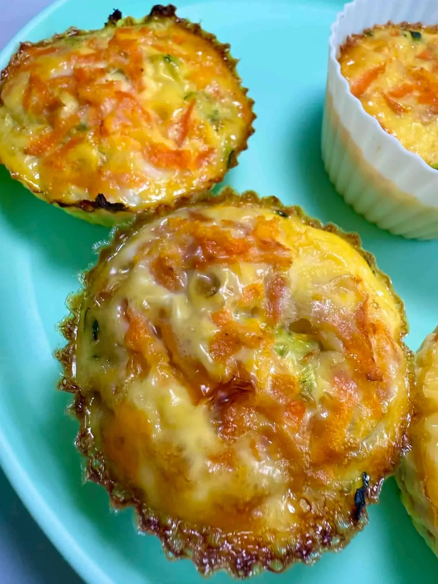 Four baked egg muffins in silicone cases on toddler plate